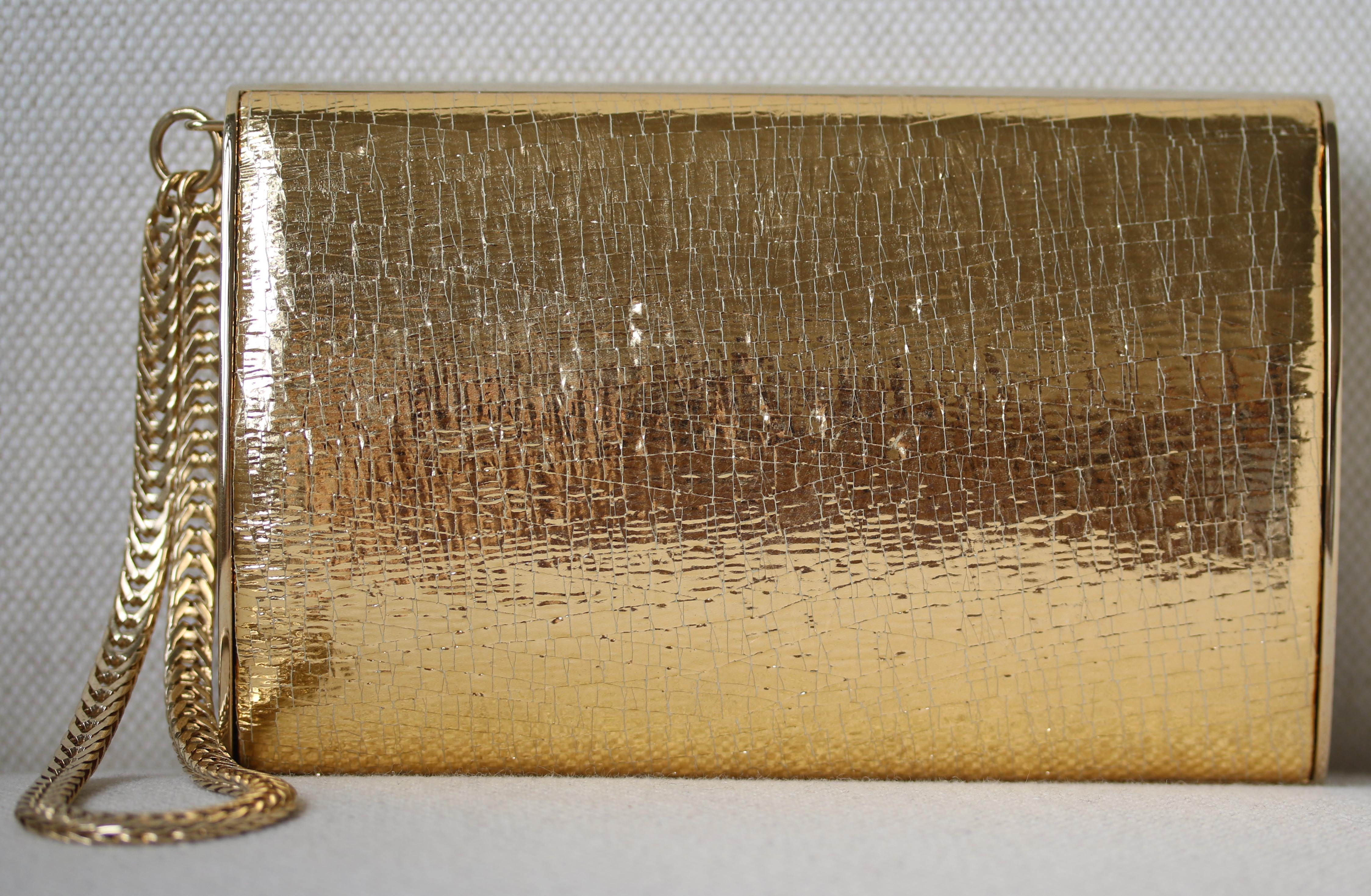 Jimmy Choo gold leather and metal clutch with wristlet chain. Satin-lined interior. Made in Italy.

Dimensions: Approx. D 4 cm  x H 10 cm  x W 15 cm 

Condition: Excellent pre-owned condition, no sign of wear except superficial scratching to