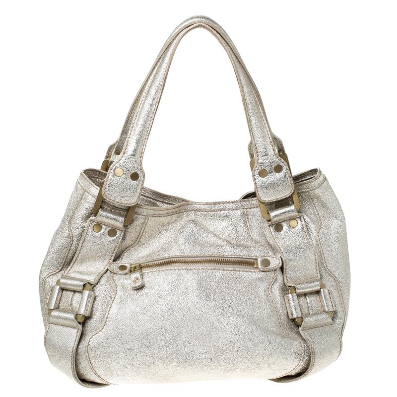 This Malena satchel by Jimmy Choo is high on sophistication. Crafted from gold leather, it features dual top flat handles along with a zipper pocket on the front. The zip-enclosed suede interior is spacious for your essentials. This bag will be a