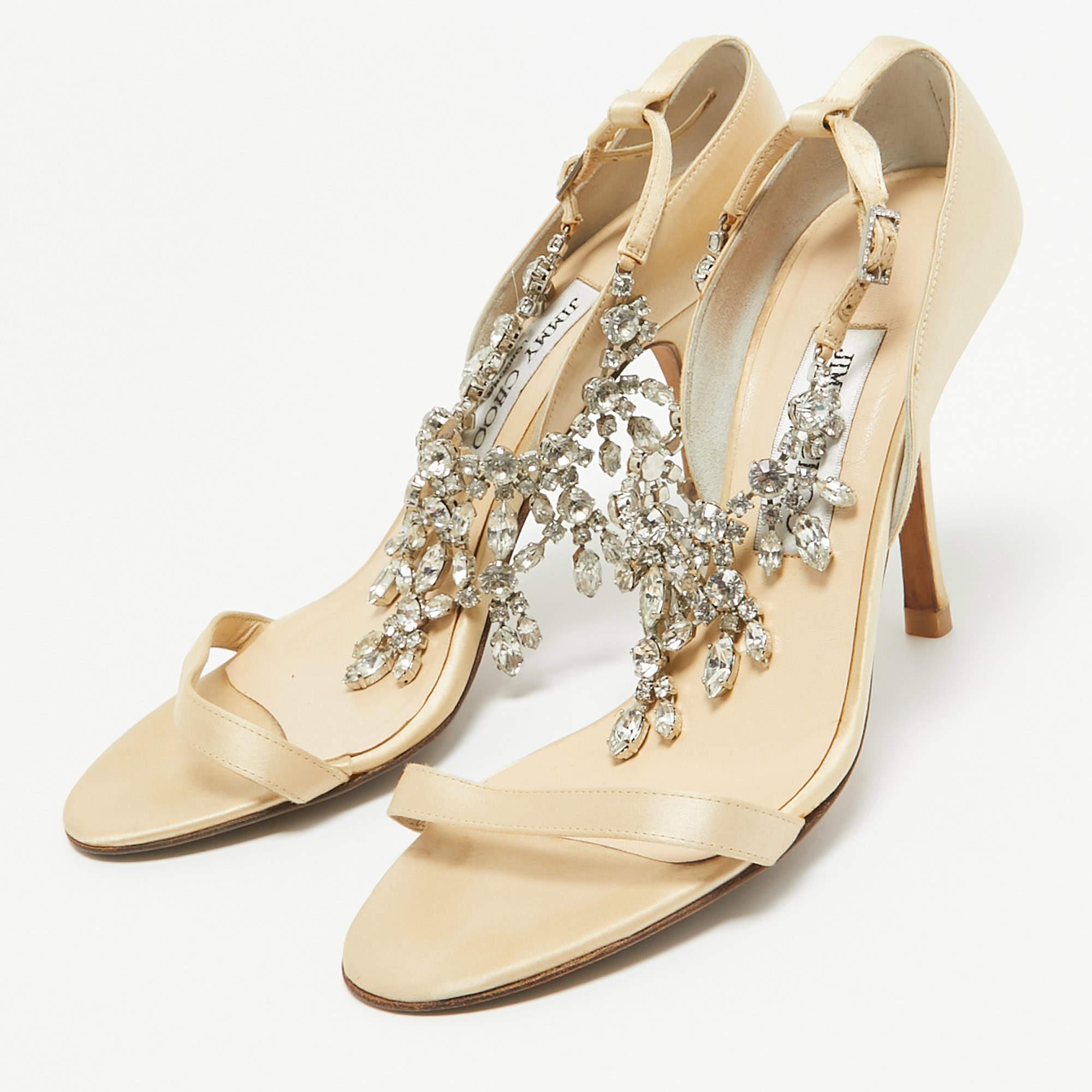These sandals from Jimmy Choo will lend a stylish and glamorous edge to your feet. This beautiful pair of satin sandals carries a pretty shade of gold. It has crystal embellished ankle strap buckled closures and 10.5cm heels. They are styled with