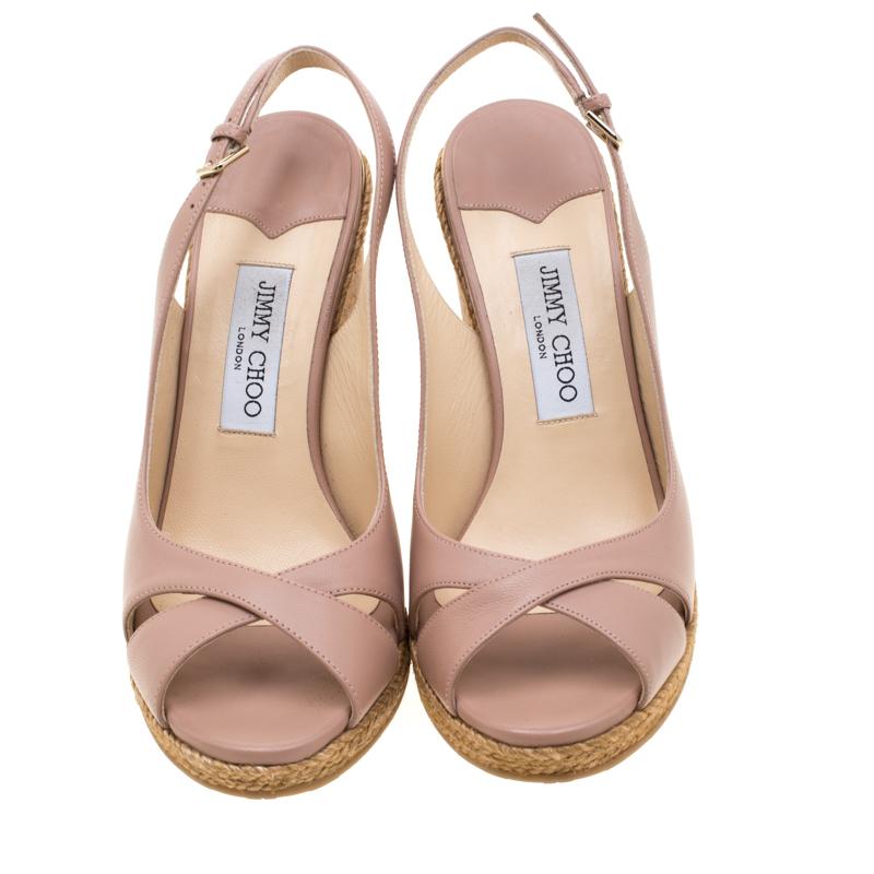 These lovely sandals from the fashion house of Jimmy Choo will be your ideal companion for casual or formal outings. Crafted from pale pink leather, they feature espadrille trims and slingback straps with buckle closures. These cork wedges stand
