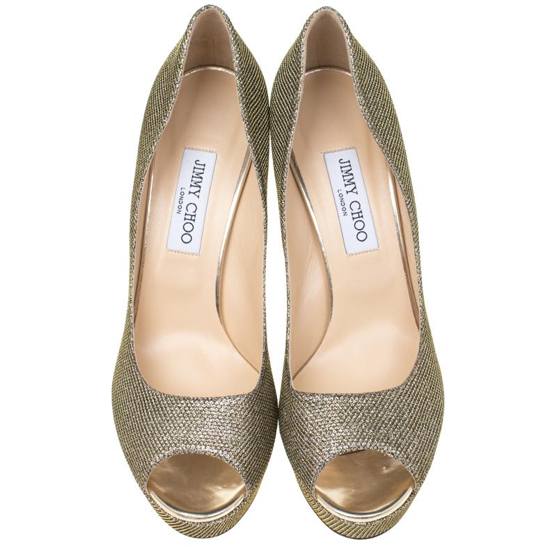 Flaunt an elegant look in this pair of Dahlia pumps from Jimmy Choo. Ideal for glitzy events, they are crafted from metallic light bronze, lamè glitter fabric and come with peep toes, platforms, and 12.5 cm gold-tone stiletto heels. Exquisitely