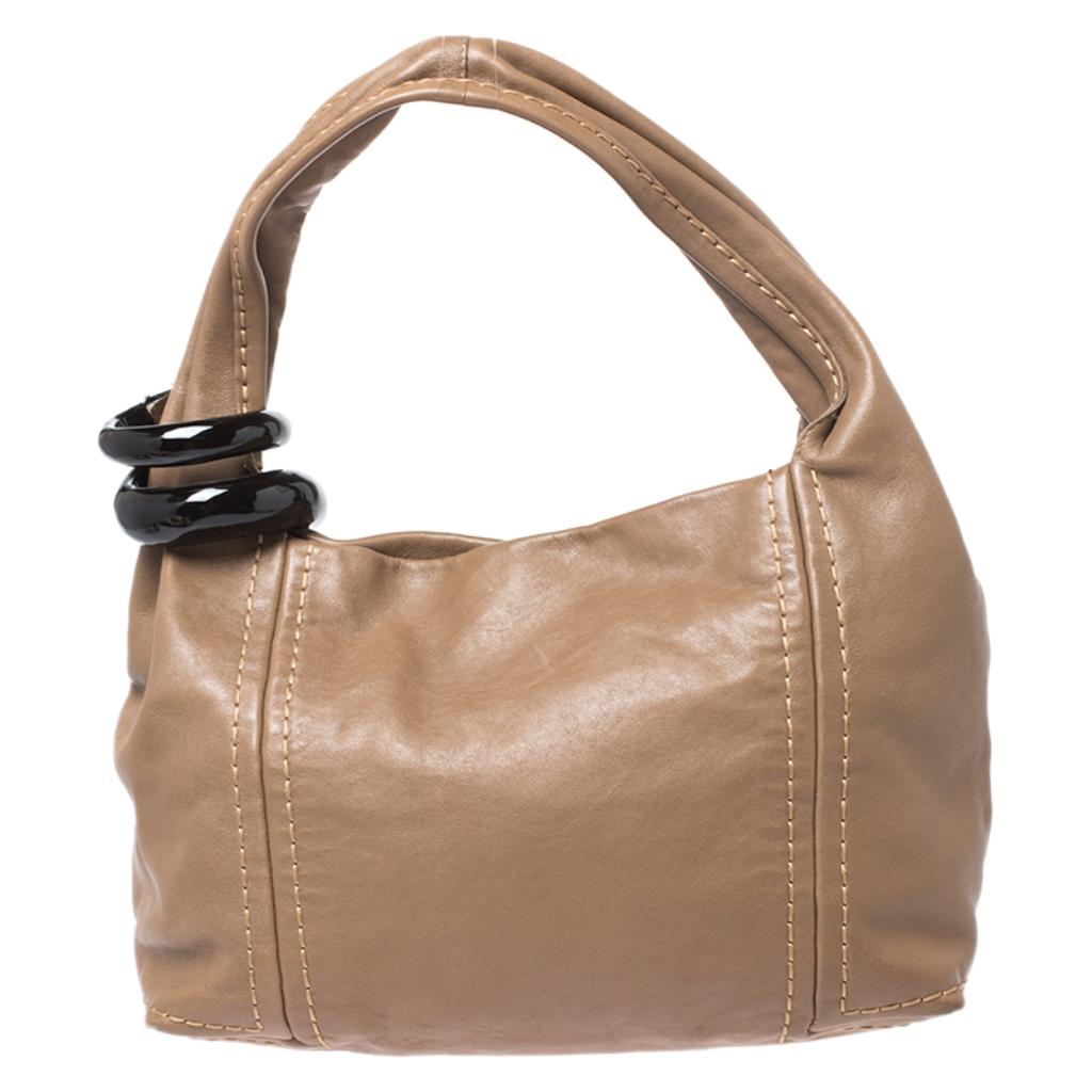 Jimmy Choo designs exude sophistication and functionality. This hobo bag is no different. Crafted in Italy, it is made from quality leather and comes in a lovely shade of light brown. The bag is held by a single handle that is adorned with an