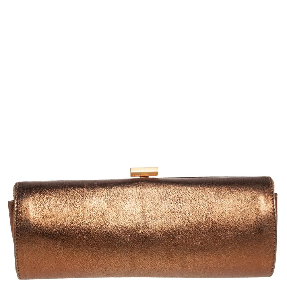 This Jimmy Choo Twill Tube clutch is created to complement all your stylish ensembles. Crafted from leather, it has a metallic bronze shade, a gold-tone metal frame, and an Alcantara-lined interior.

