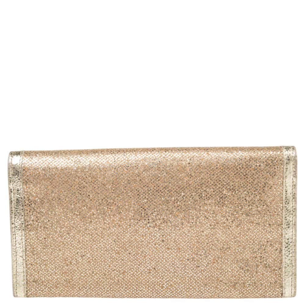 The Jimmy Choo Reese clutch is both practical and glamorous. Crafted from gold glitter and patent leather, this Italian-made wallet is presented in a streamlined silhouette. The front flap with a gleaming logo plaque opens to a leather and canvas