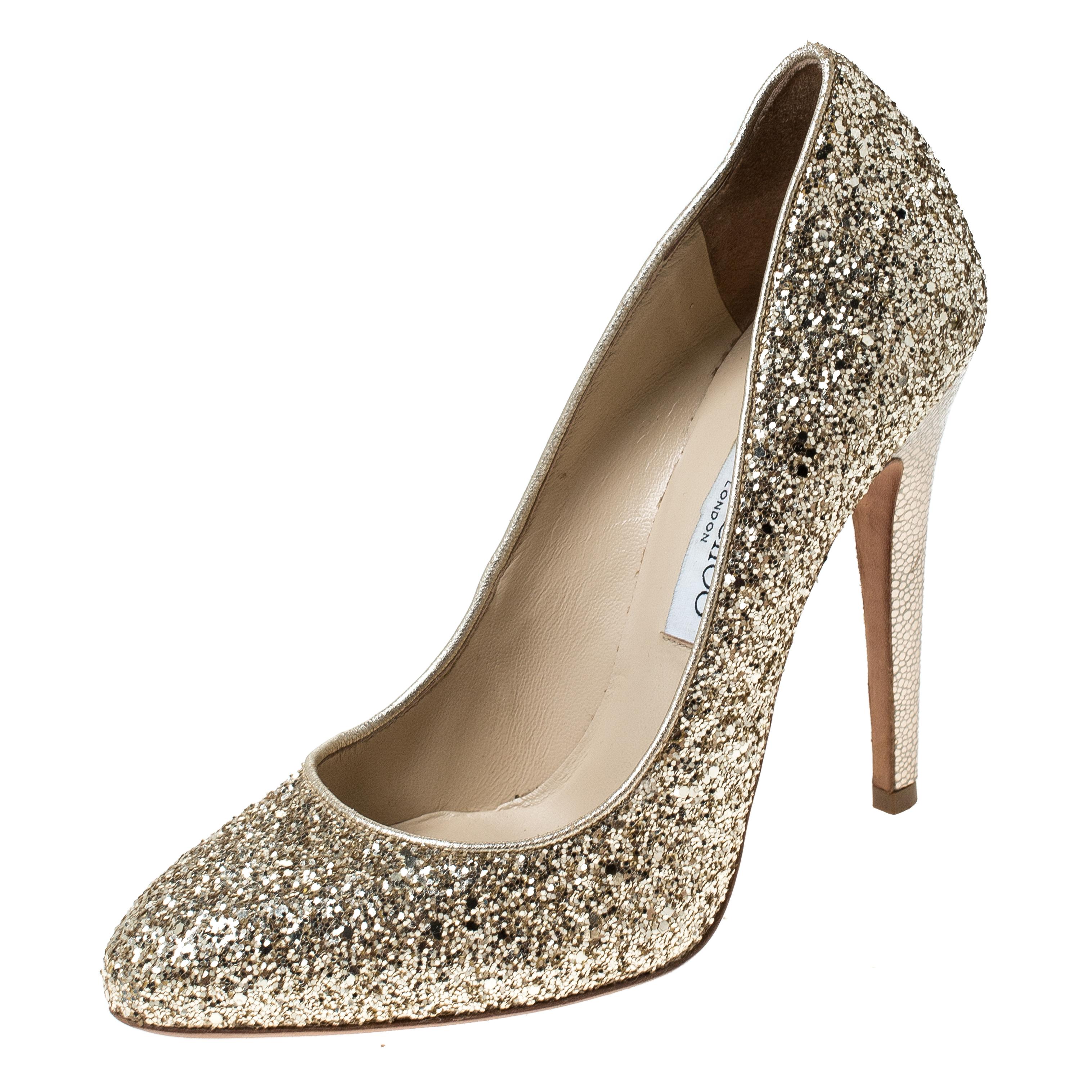 Elevate your style statement a notch higher with these Victoria pumps from Jimmy Choo! The metallic gold pumps are crafted from glitter and feature almond toes. They come equipped with comfortable leather-lined insoles and 12 cm high