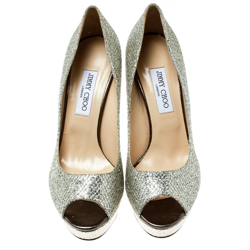 Look no less than a diva in these Dahilia pumps from Jimmy Choo. Crafted from metallic gold lamè fabric, they are lined with leather on the inside. This pair carries 12 cm high heels with supporting platforms. Complete with peep toes, you can