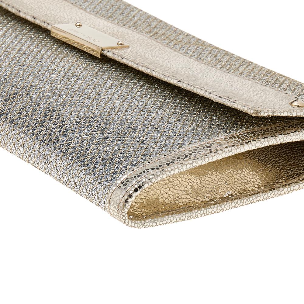 The Jimmy Choo Reese Clutch is both practical and glamorous. Crafted from metallic gold leather and glitter, this clutch is presented in a simple silhouette. The front flap with a gleaming logo plaque opens to a fabric-leather interior housing card