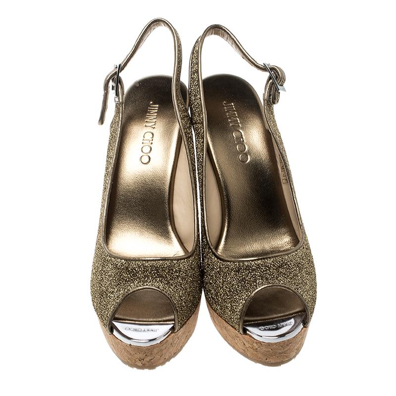 These Jimmy Choo sandals make a classic and elegant choice that can be paired with both jeans and skirts alike. Set on a cork wedge sole, this pair comes with a gorgeous metallic gold lurex fabric body and features a slingback closure secured with a