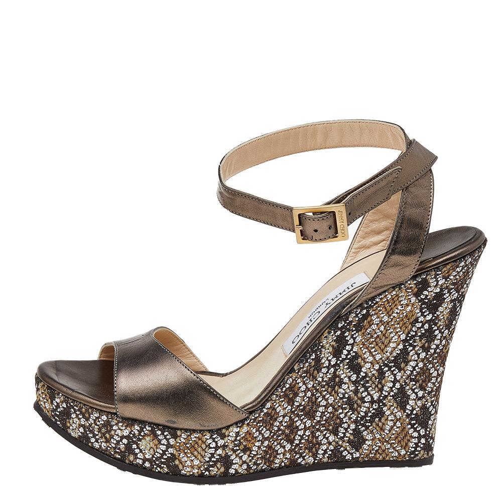 These sandals by Jimmy Choo deliver style and comfort. Crafted in Italy from metallic leather, these sandals have a lovely silhouette. They are styled with open-toes, buckled ankle straps, platforms, 12.5 cm wedge heels, leather lining, insoles, and