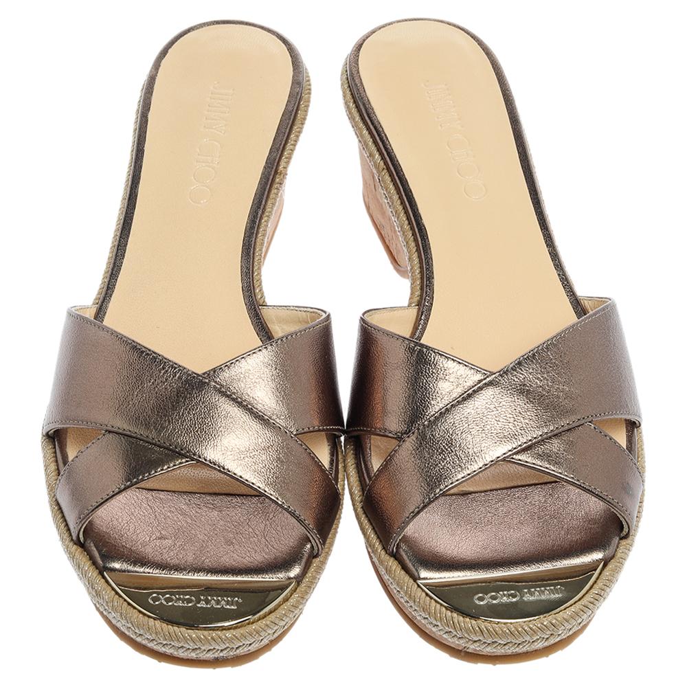 Diese hübschen Jimmy Choo-Slides verleihen Ihnen das richtige Maß an Stil und Glanz. Sie haben überkreuzte Riemen aus olivgrünem Metallic-Leder und 6 cm hohe Korkkeile auf dem Vorderblatt. Sie sind hübsch und leicht zur Schau zu stellen.

