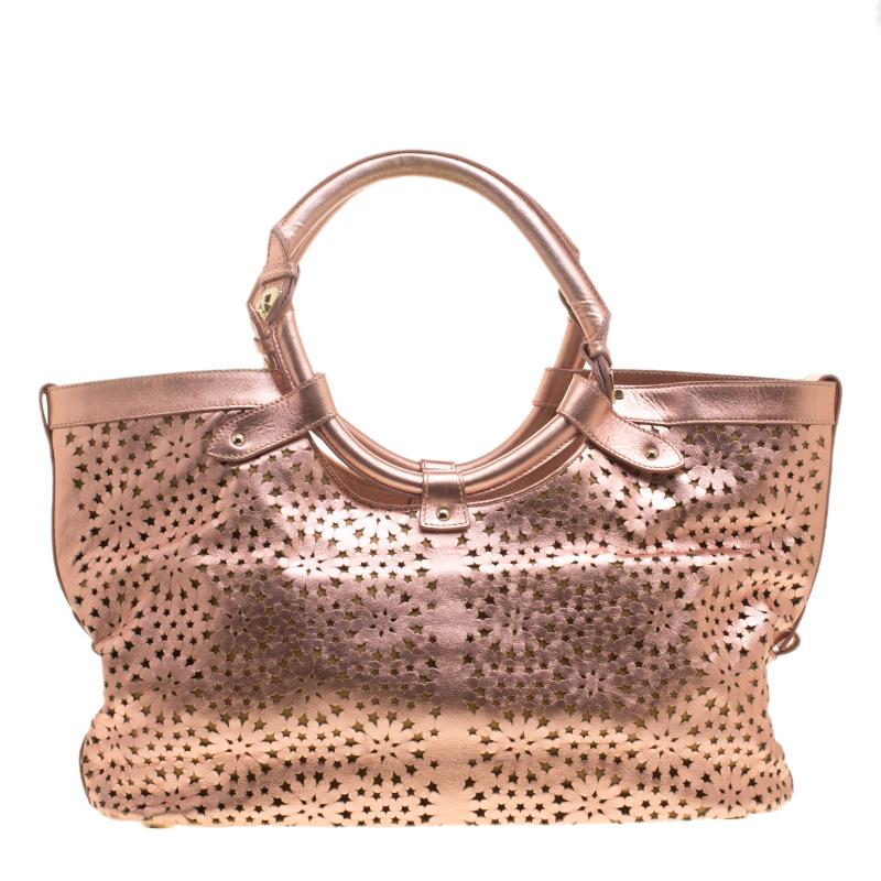 The metallic rose gold shade will stand out every time you swing this beauty. Get your hands on this beautiful leather tote to nail a picture perfect look. It is from Jimmy Choo and it is designed with laser cuts, two top handles, and a spacious