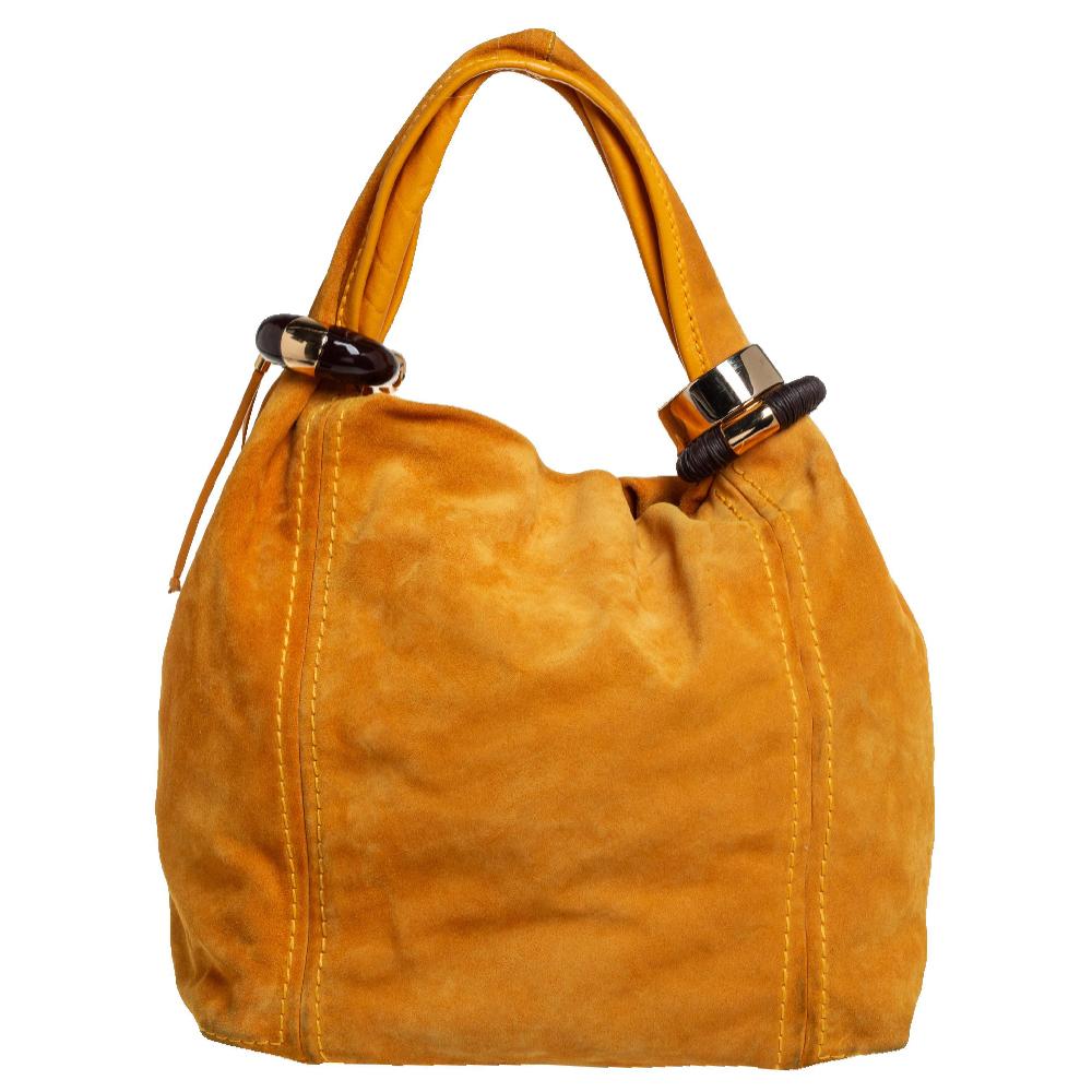 This lovely Saba hobo comes from the iconic house of Jimmy Choo. Crafted in Italy, it has been made from suede in a lovely mustard shade. It is held by a single handle that is beautified with gold-tone accessories. The bag opens to a spacious