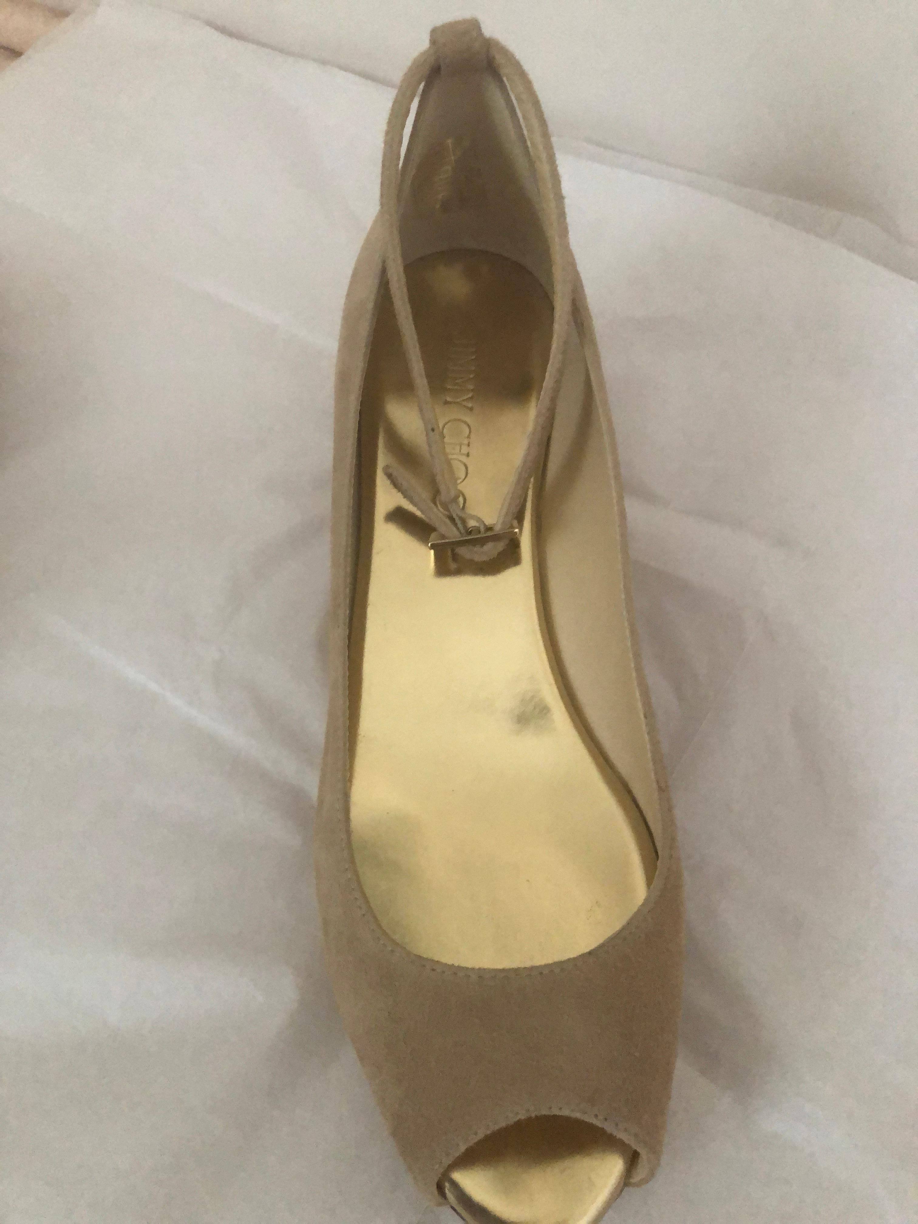 Joli daim de couleur nude avec des cales en liège et des semelles en caoutchouc. Elles sont avant-gardistes et confortables. Elles présentent des orteils ouverts, une bride à la cheville réglable, un talon compensé en liège avec le logo Jimmy Choo