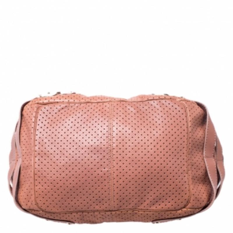 Make everyone nod in approval when you step out swinging this nude pink Jimmy Choo Bardia bag. It has been crafted from perforated leather and styled with buckle detailing on the sides. The interior is suede-lined and the bag is completed with dual