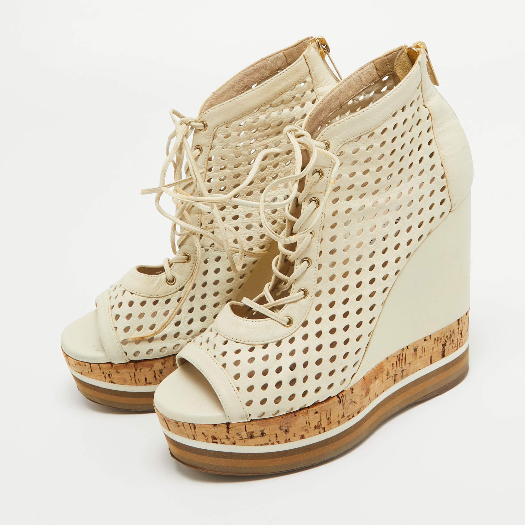 Apportez une touche d'élégance à votre look du jour avec ces bottines Jimmy Choo. Ils sont dotés d'orteils ouverts, d'une fermeture à lacets et à glissière et de talons compensés.