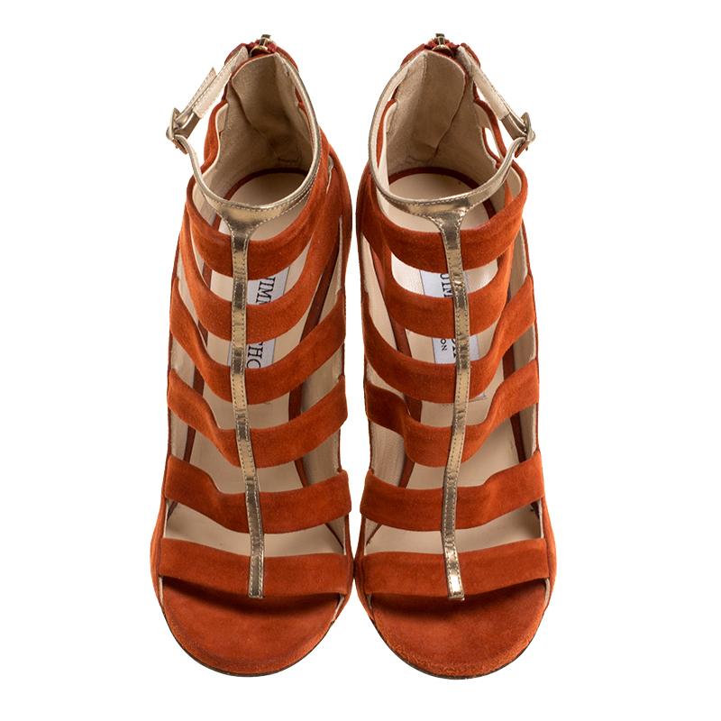 These Jimmy Choo booties exude an aura of bold style and class. The pair comes crafted with orange-coloured suede with bronze leather trims. The intriguing cage design of these sandal booties is accompanied with open toes, making them a charming