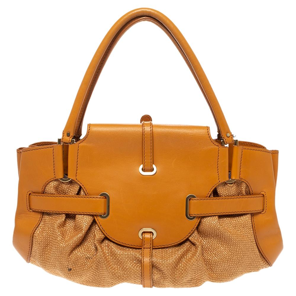 Diese Tulita-Tasche von Jimmy Choo ist ein absolutes Muss für alle Fashionistas! Sie ist aus Leder und Raffiabast gefertigt, hat einen orangefarbenen Farbton und eine einzelne Kette, an der Sie sie vorführen können. Die Tasche ist mit einem