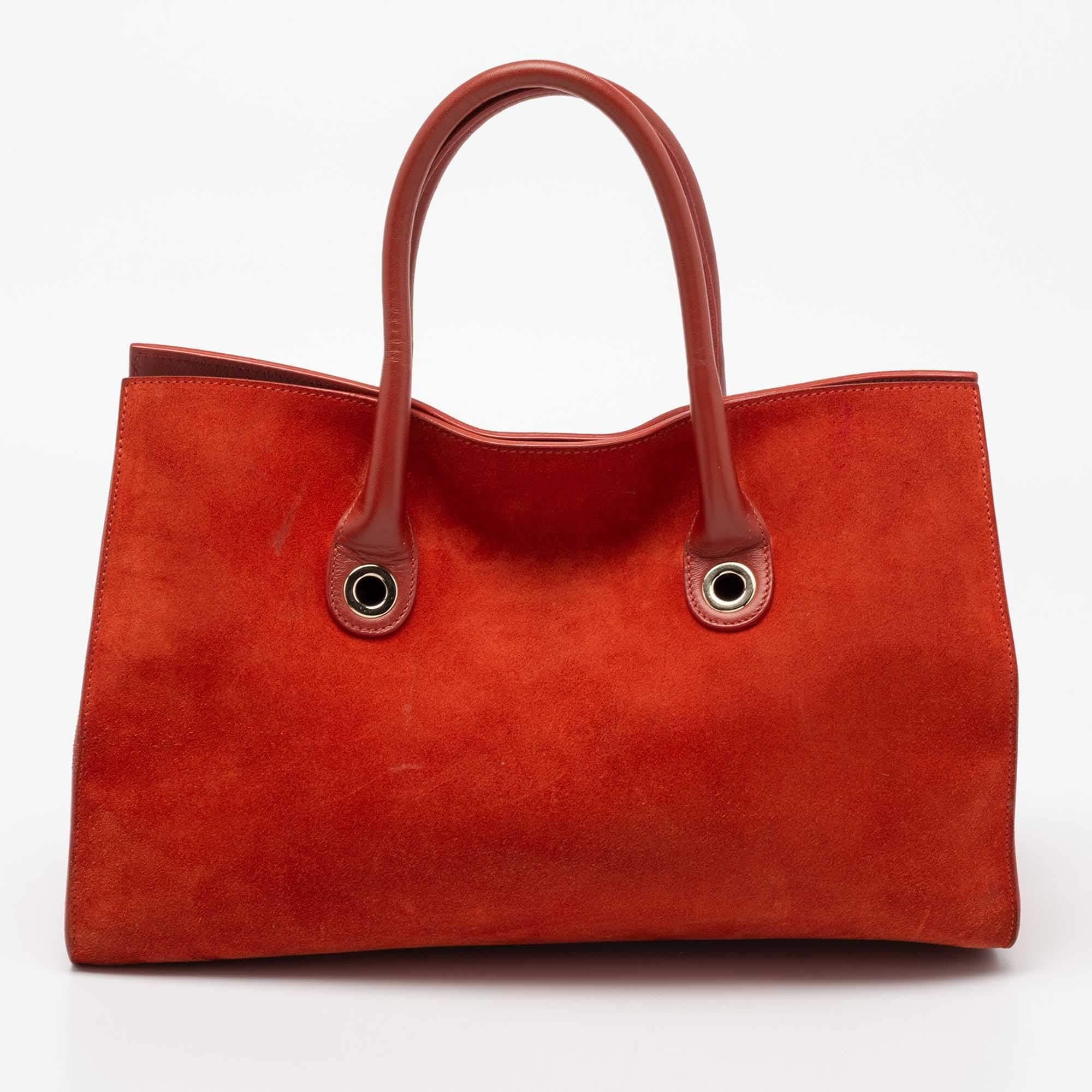Coming from Jimmy Choo is this pretty orange tote that is the perfect day bag. It is crafted from suede and leather into a structured shape. The bag flaunts gold-tone details, dual handles, and a capacious interior for your belongings. It will look