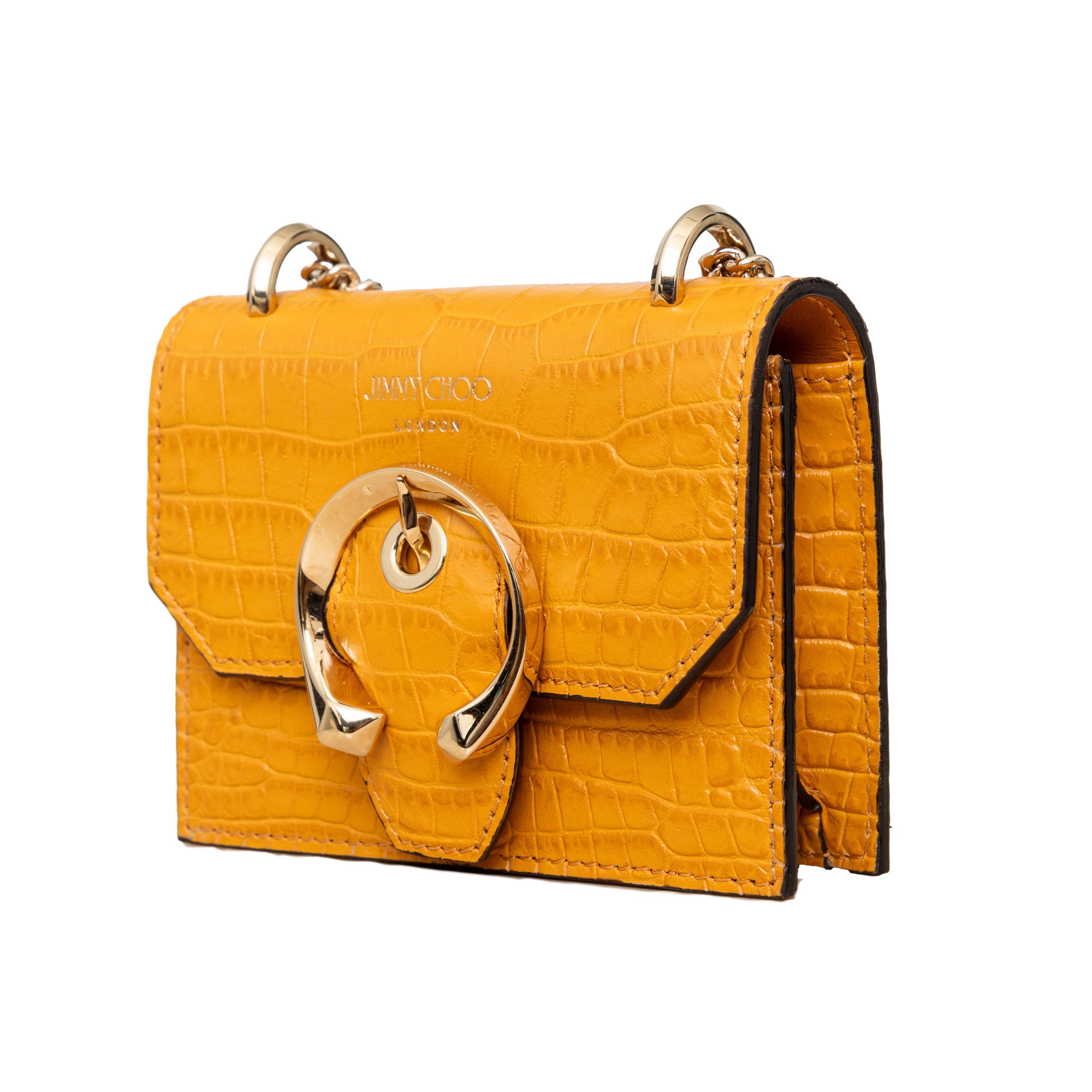 The Jimmy Choo Paris Mini Bag is expertly crafted in Italy from snakeskin embossed leather in a stunning mustard yellow color. With a long crossbody chain, snap closure, and statement gold tone buckle, this mini marvel exudes sophistication and