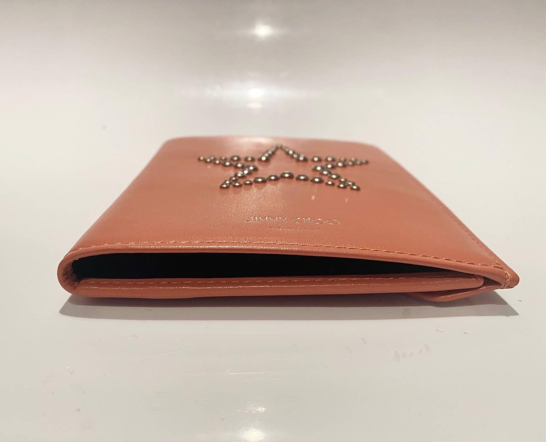 Jimmy Choo Pink Nappa leather 'Analya' star motif passport holder by Jimmy Choo. Interior pocket. Silver-tone stud star detailing at front.

Measurements: Snap closure at back. 5.5