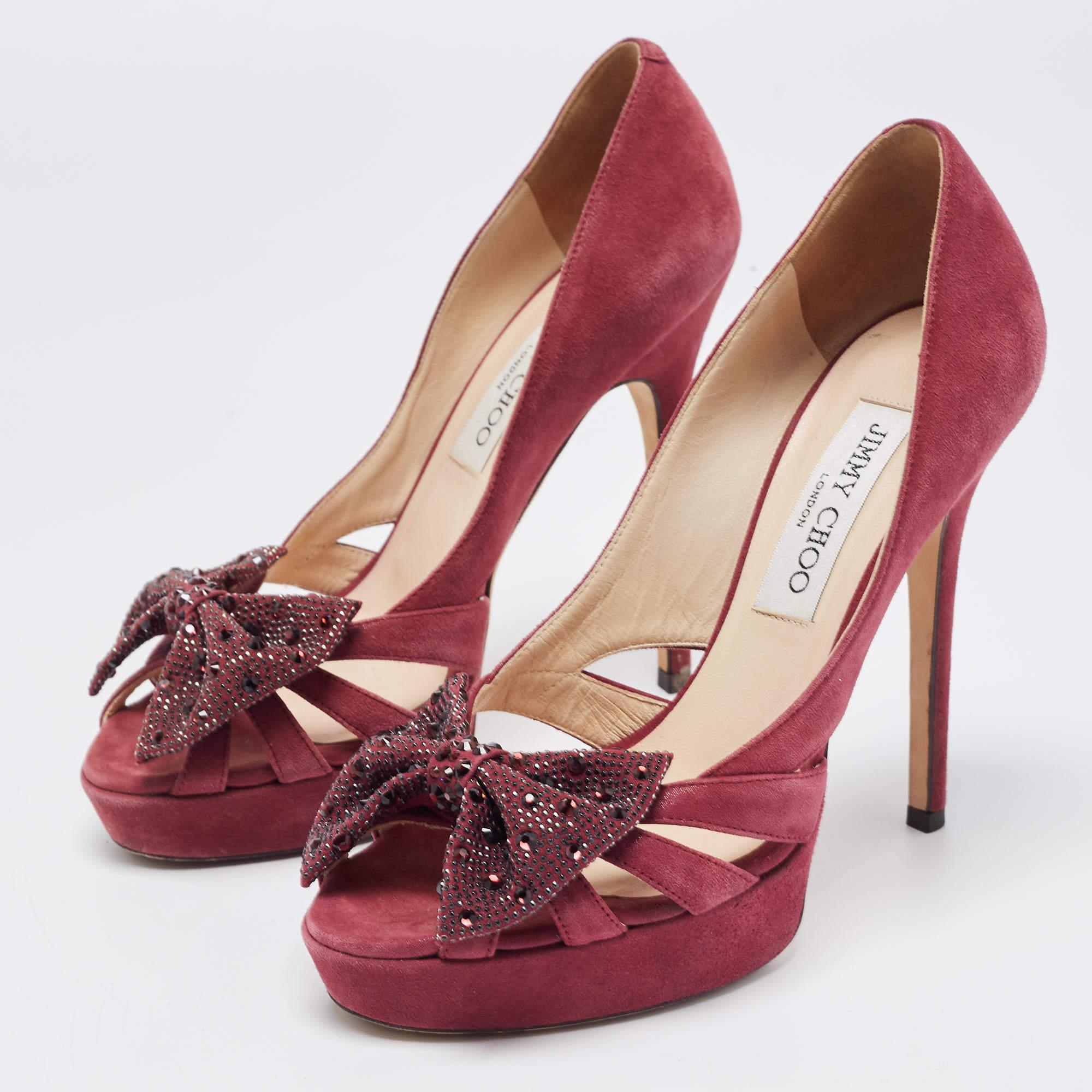 Fall head over heels in love with this pair of purple pumps from Jimmy Choo. Crafted from suede and styled with stiletto heels, they carry a glorious exterior with cutouts and a stunning crystal embellished bow that will catch glances. The pumps are
