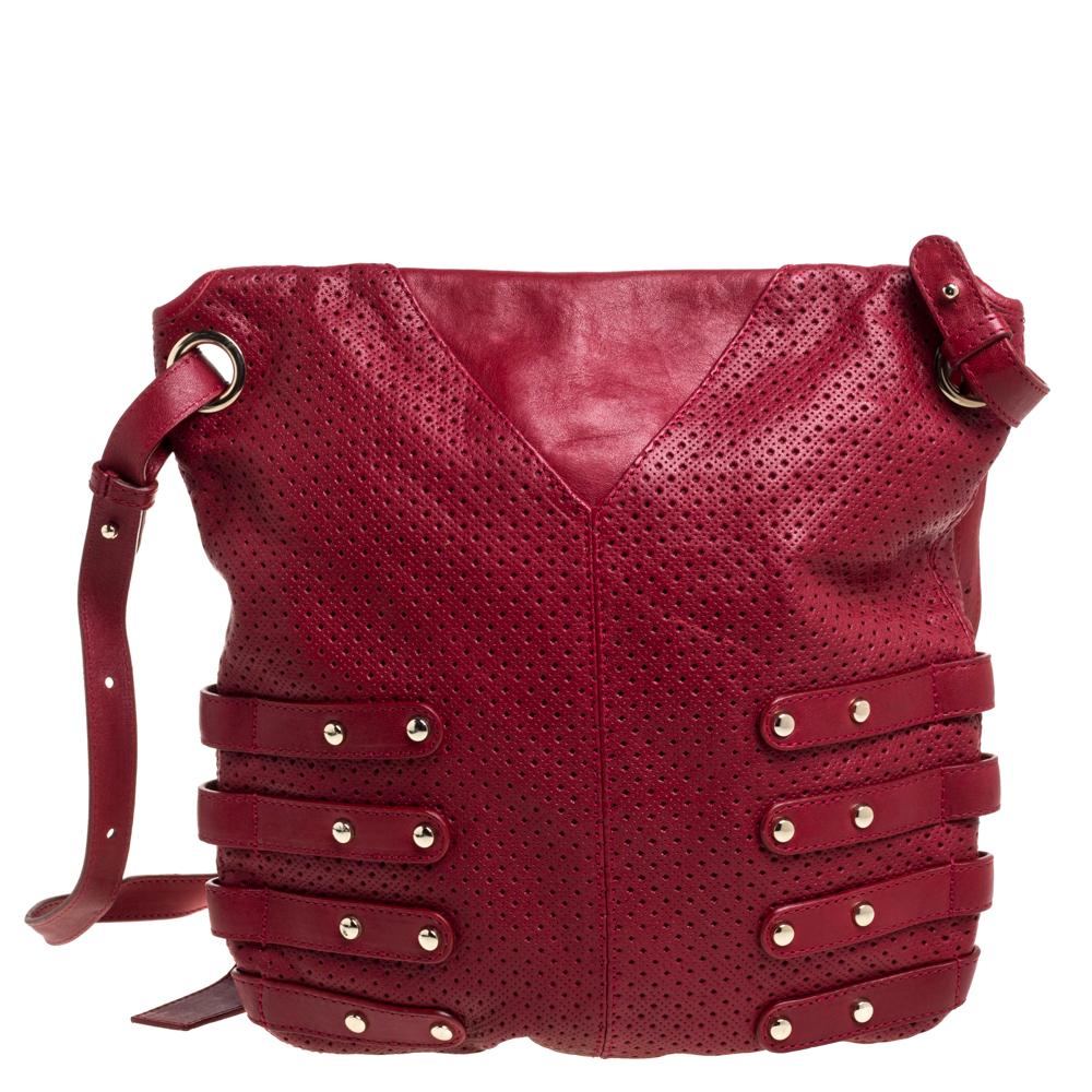 Easily get through your day with this edgy holdall Brina shoulder bag by Jimmy Choo. It is made from perforated red leather with gold hardware. It is also adorned with biker detailed side buckle straps along with open side pockets, a leather tab