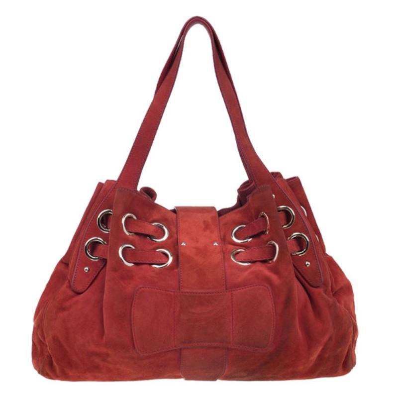 This gorgeous red Jimmy Choo Suede Ramona Bag features distressed red suede and a relaxed slouchy shape. It has two straps that lace through stylish metal eyelets. It is accented with silver-tone hardware. This tote comes with two flat leather