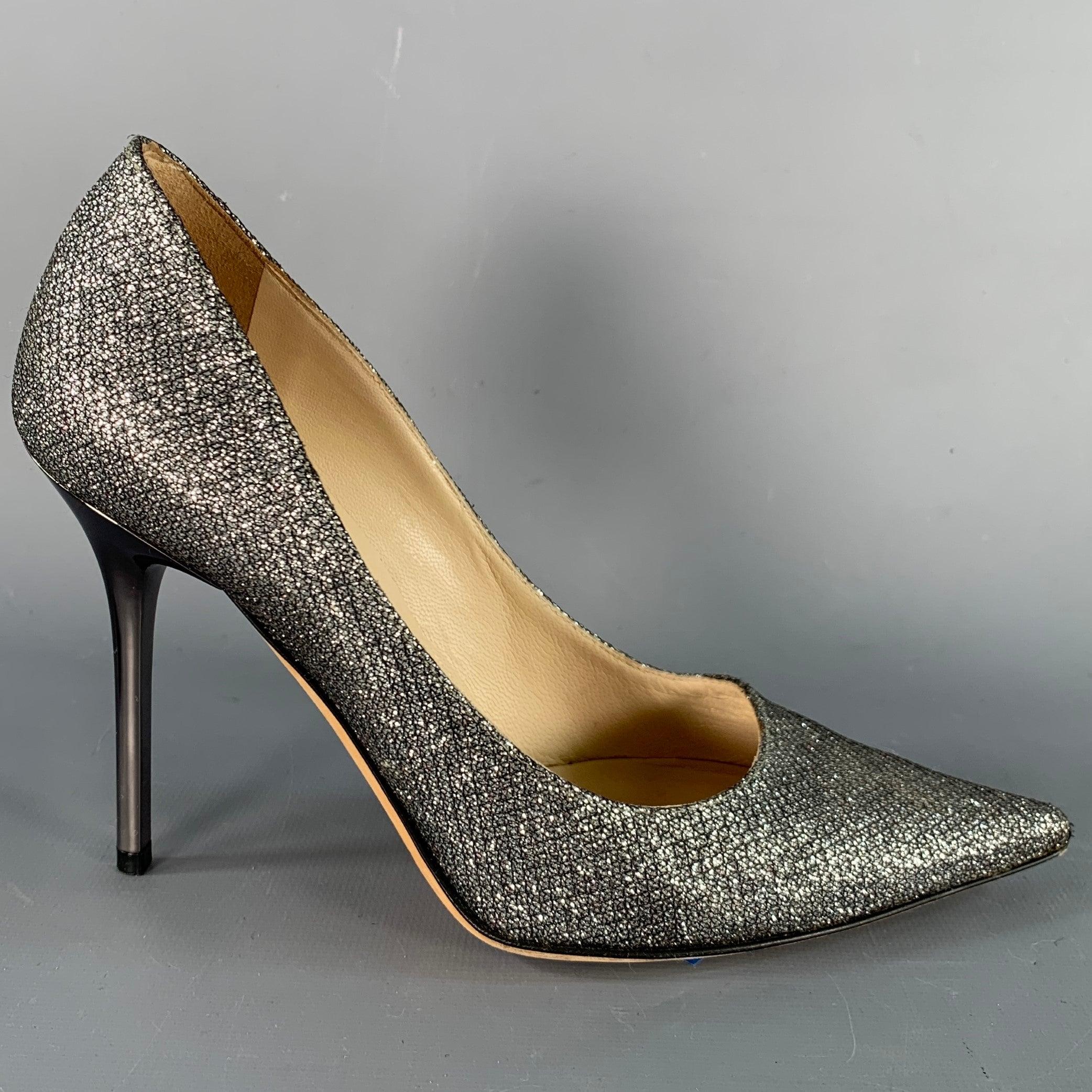 JIMMY CHOO pumps
in a silver tone glittered fabric featuring a silver tone metal stiletto heel, pointed toe, and slip on closure. Made in Italy.Very Good Pre-Owned Condition. 

Marked:   IT 34 

Measurements: 
  Heel: 3.75 inches 
  
  
 
Sui