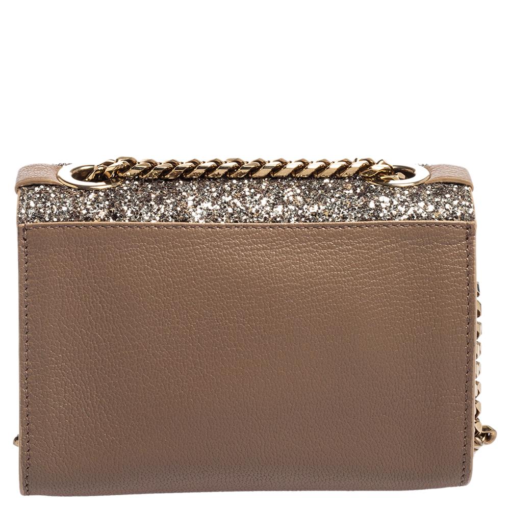 This stunning Rebel crossbody bag from Jimmy Choo is high on appeal and style. The bag is crafted from leather and designed with a silver glitter flap that has a flip lock and leads way to a suede-lined interior. The gold bag is held by a chainlink