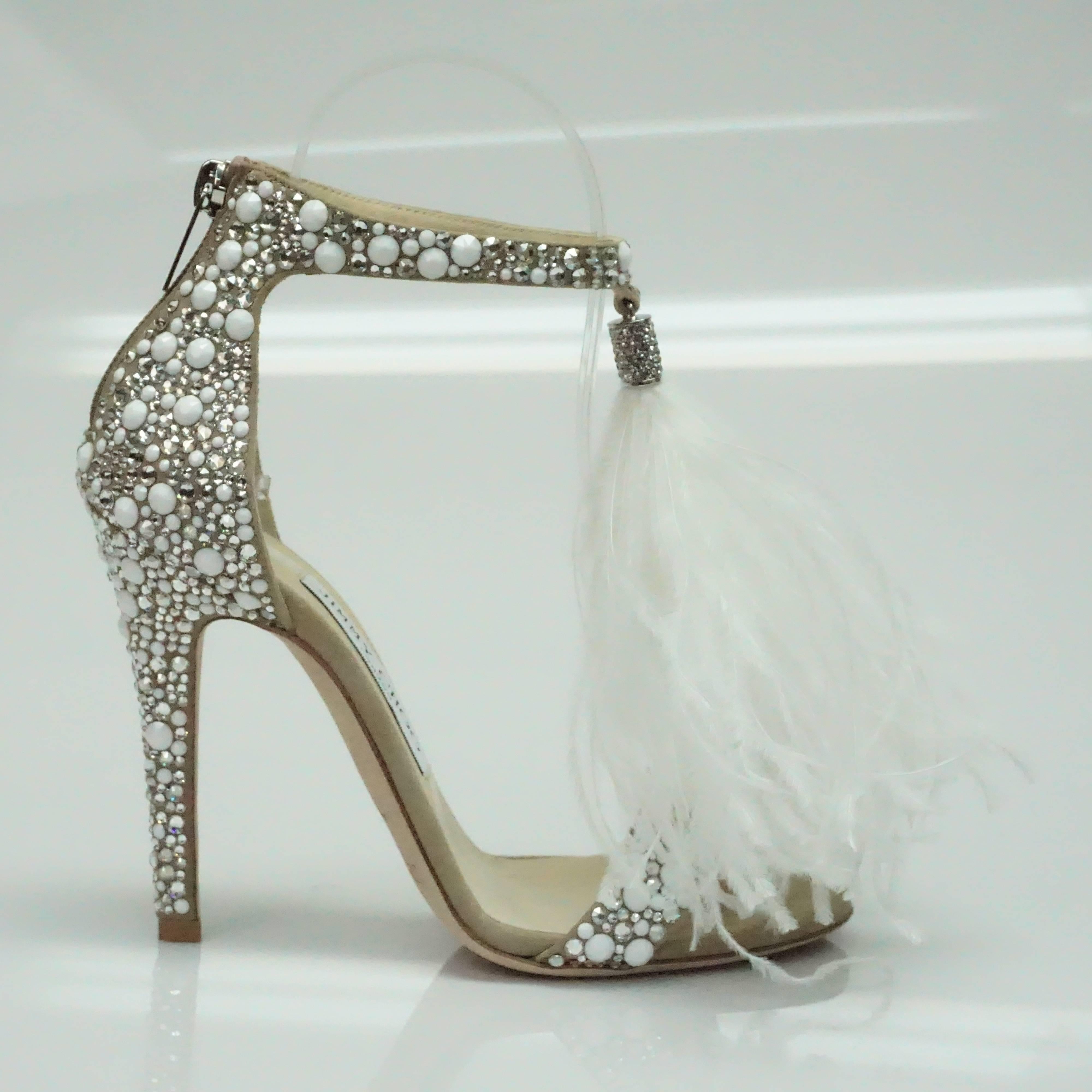 Jimmy Choo Viola White/Crystal Mix Wedding Sandals - NEVER USED - 36  These spectacular, sold out Wedding shoes are a nude color suede and are completely covered with white stones and crystals. They have a white hanging feather in the front hanging