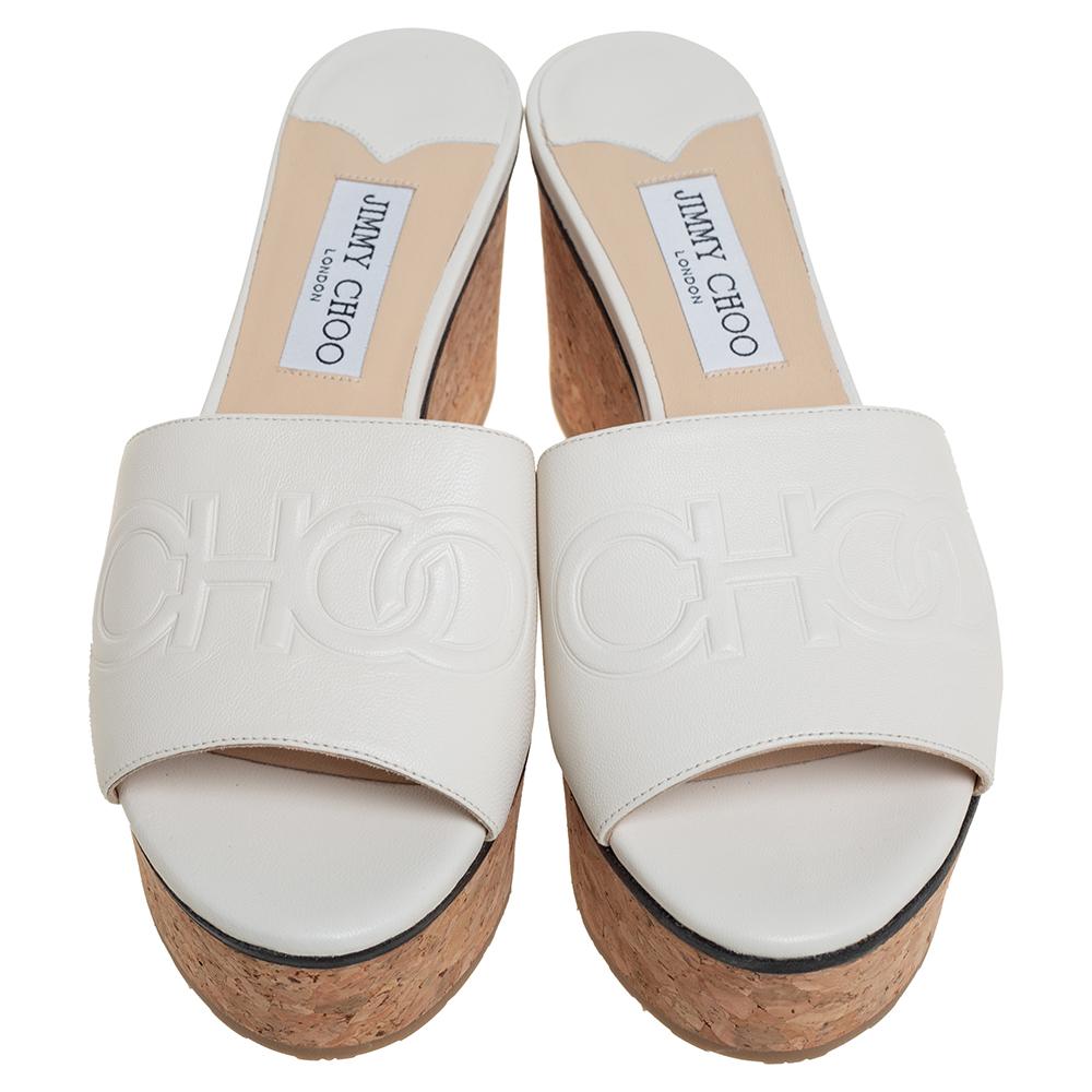These lovely Jimmy Choo slide sandals will bring you the right amount of style and shine. They feature logo-detailed straps on the vamps made from white leather and 7 cm cork wedges. They are pretty and easy to flaunt.

Includes: Original Dustbag,