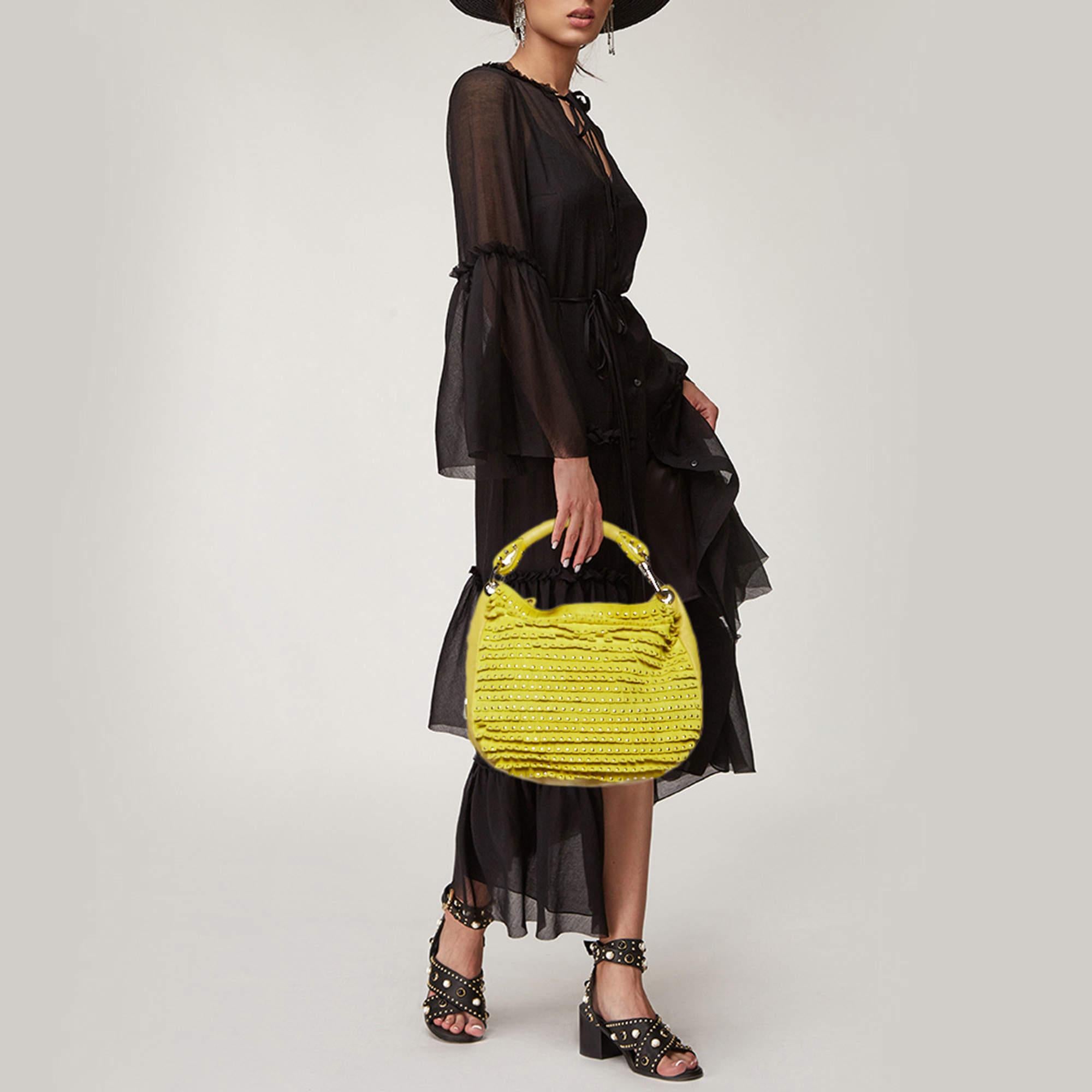 Step out in style by adorning this remarkable hobo by Jimmy Choo. Made from leather in a yellow hue  it features fringes on the front and star shaped studs. It is held by a single handle and has a spacious interior to store your essentials.