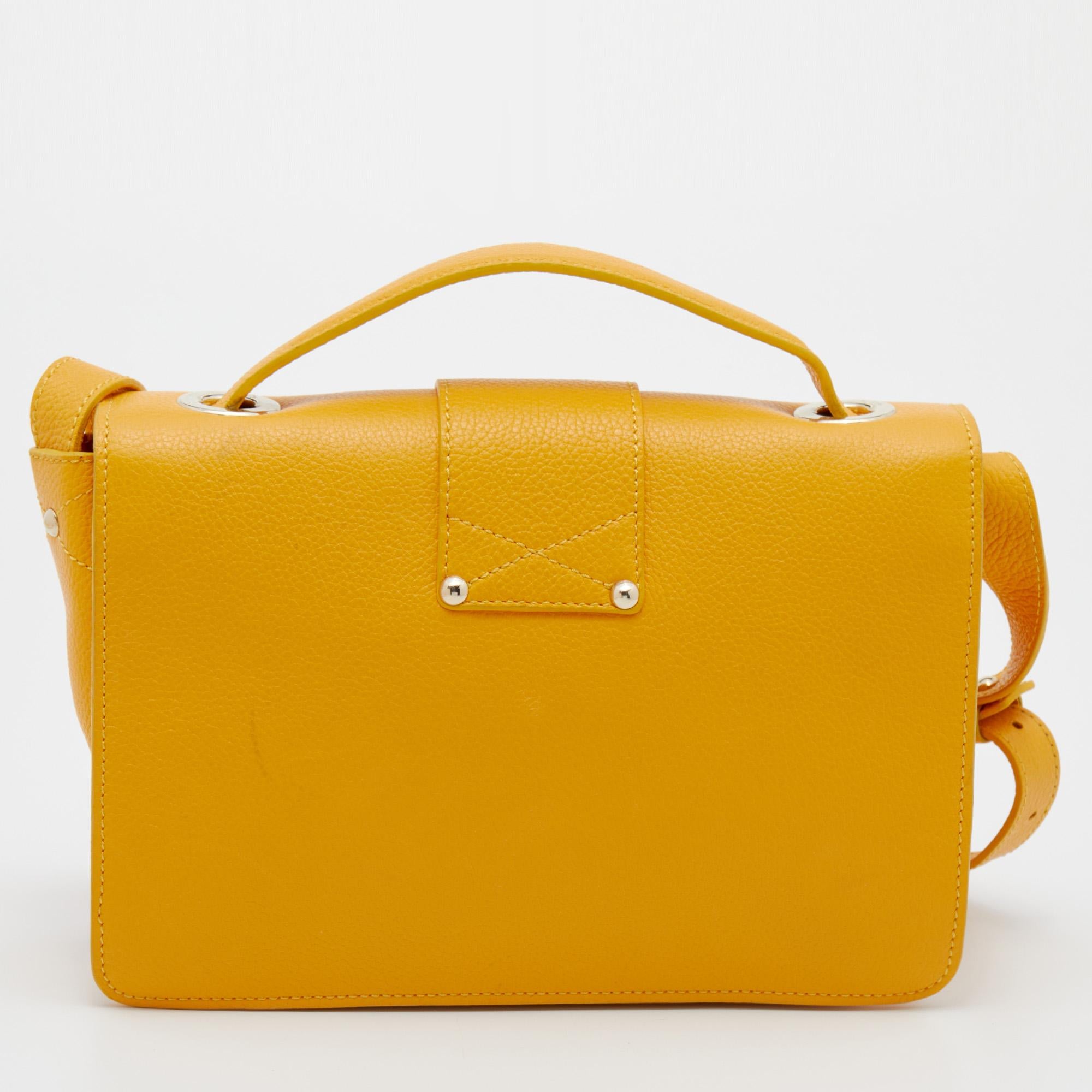 This lovely Rebel top handle bag from Jimmy Choo is high on appeal and style. It is crafted from leather and designed with a flap that has a gold-tone lock leading to an Alcantara-lined interior. The bright yellow bag is held by a top handle and an