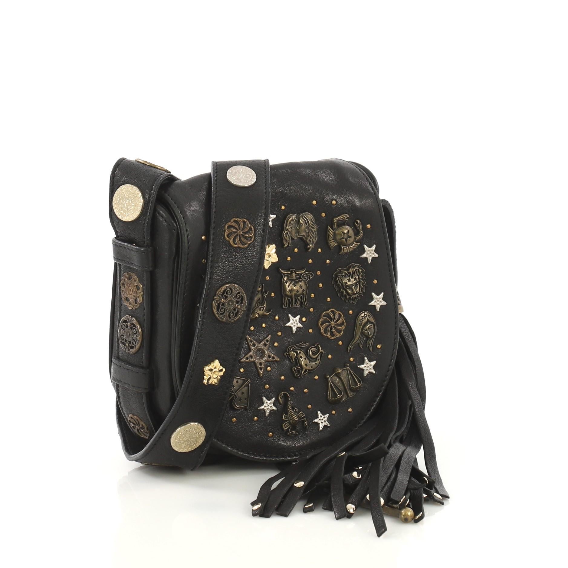 This Jimmy Choo Zena Crossbody Bag Embellished Leather Small, crafted from black embellished leather, features metal embellishment of zodiac signs, stars and moon, long leather strap, oversized tassel, and aged gold, aged silver, and brass-tone