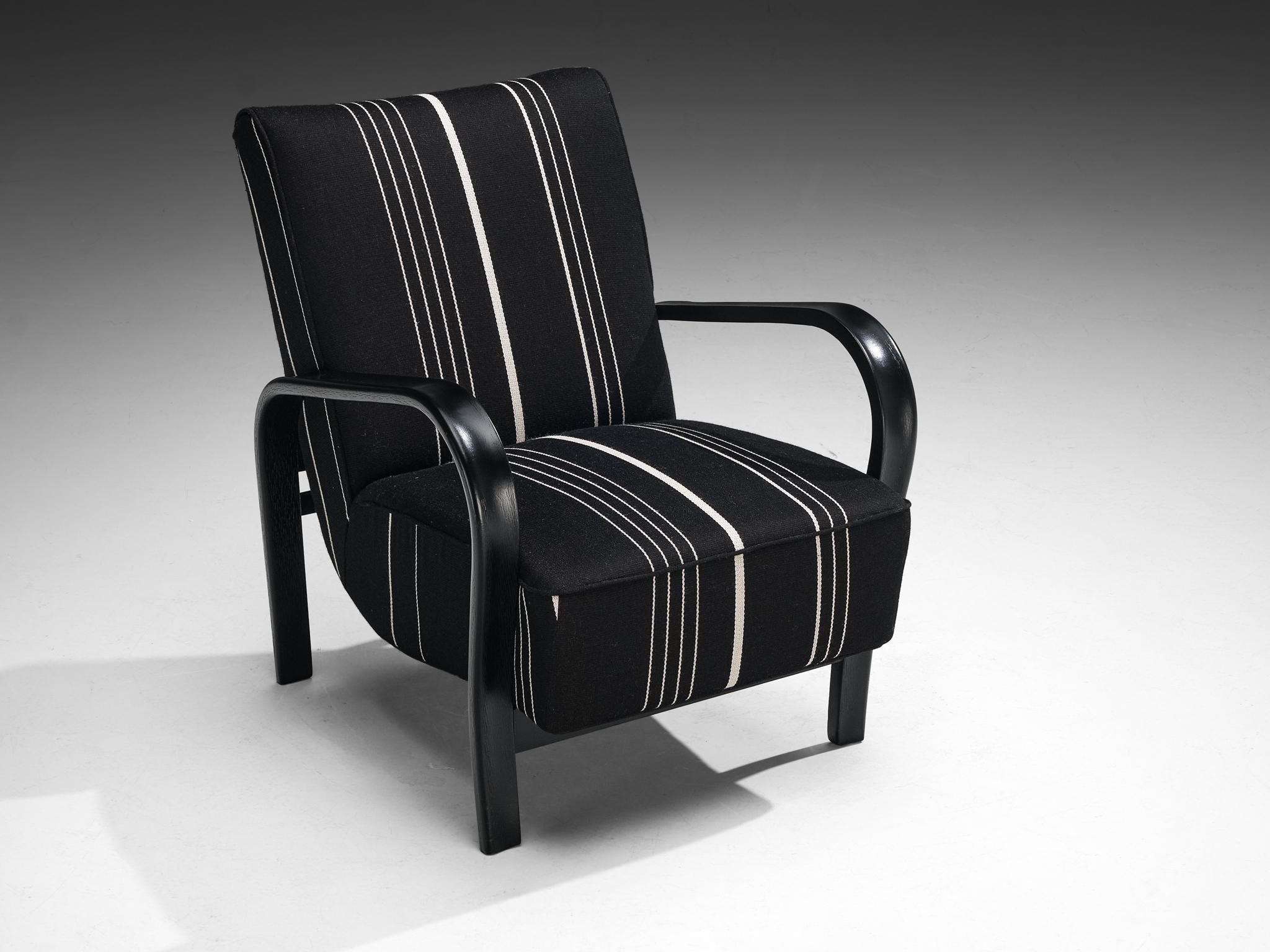 Jindrich Halabala, armchair, wood, fabric, Czech Republic, 1930s.

This dynamic lounge chair features elegantly flowing armrests, a hallmark of Halabala's iconic design. The bold, voluptuous curves of the armrests give the chair a striking and