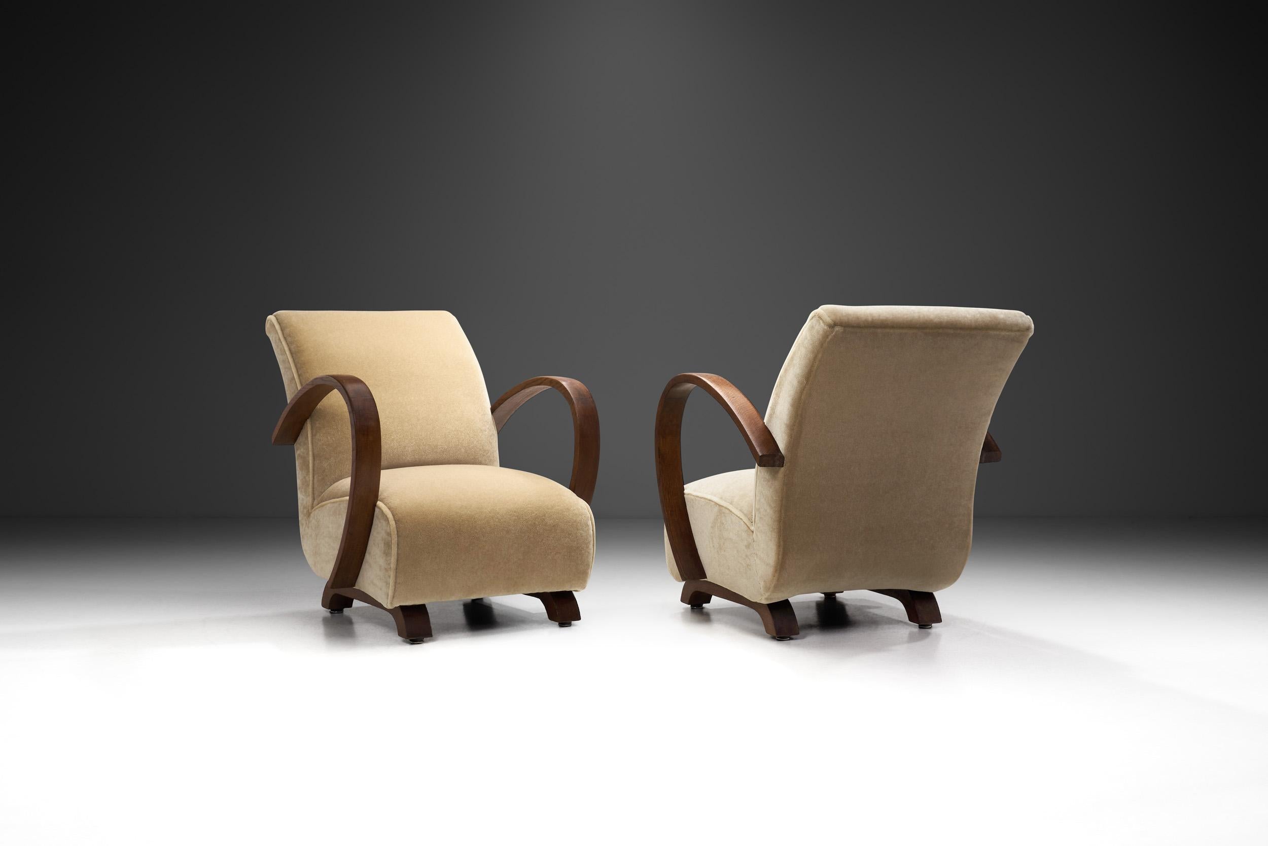 This pair of rare Jindřich Halabala lounge chairs feature the world-famous Czech designer’s most well-known design element: the steam bent, curved arms. This model exemplifies why Halabala's work is considered to be a connection between innovative
