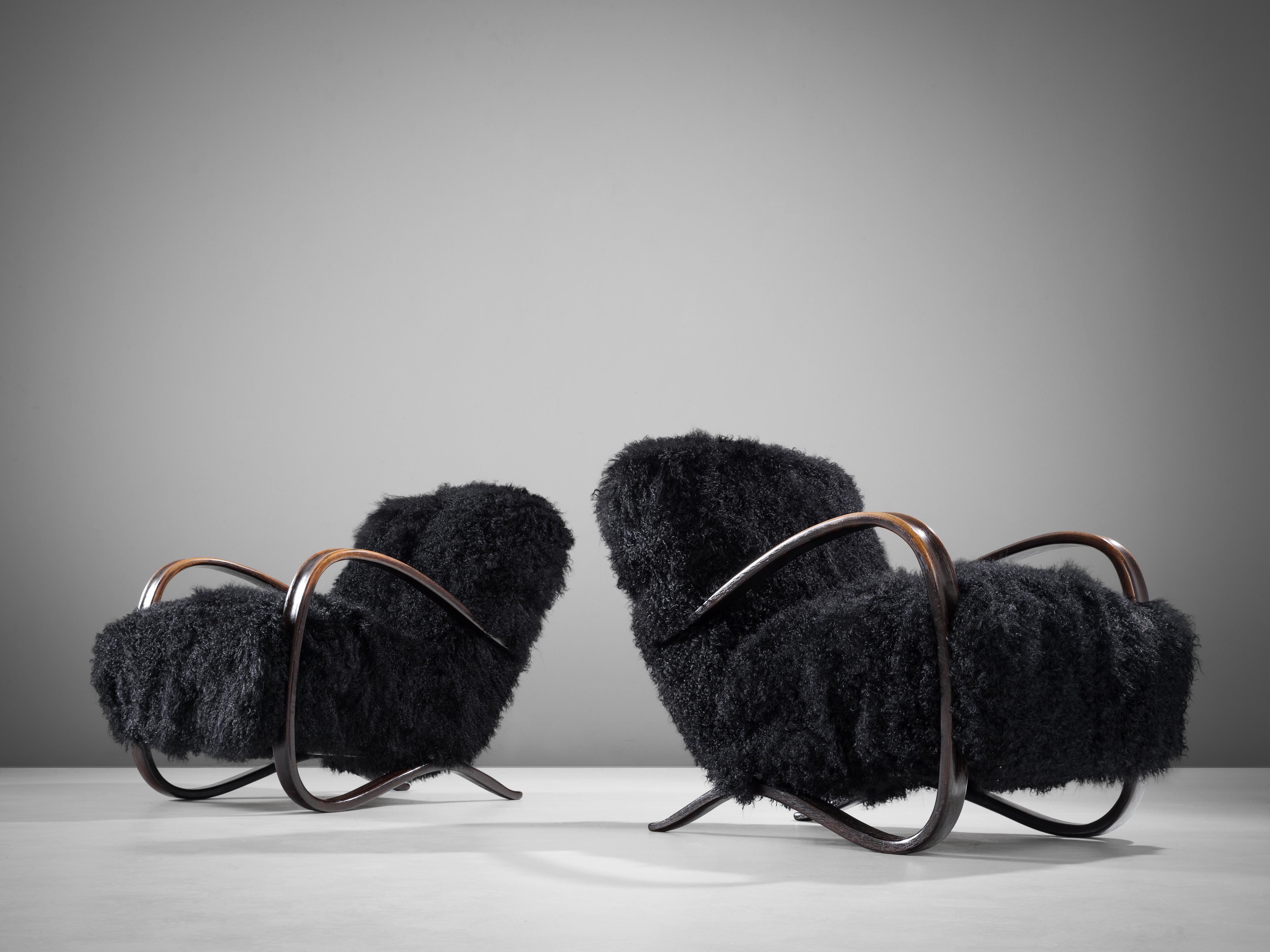 Jindrich Halabala, lounge chairs, in beech and sheepskin, Czech Republic, 1930s. 

Extraordinary pair of easy chairs with black Tibetan lambswool upholstery. These chairs have a very dynamic and abundant appearance and the fuzzy upholstery gives