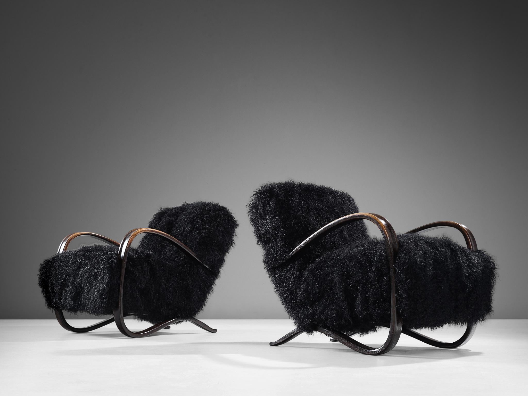 Jindrich Halabala, lounge chairs, in beech and sheepskin, Czech Republic, 1930s

Extraordinary pair of easy chairs with black Tibetan lambswool upholstery. These chairs have a very dynamic and abundant appearance and the fuzzy upholstery gives