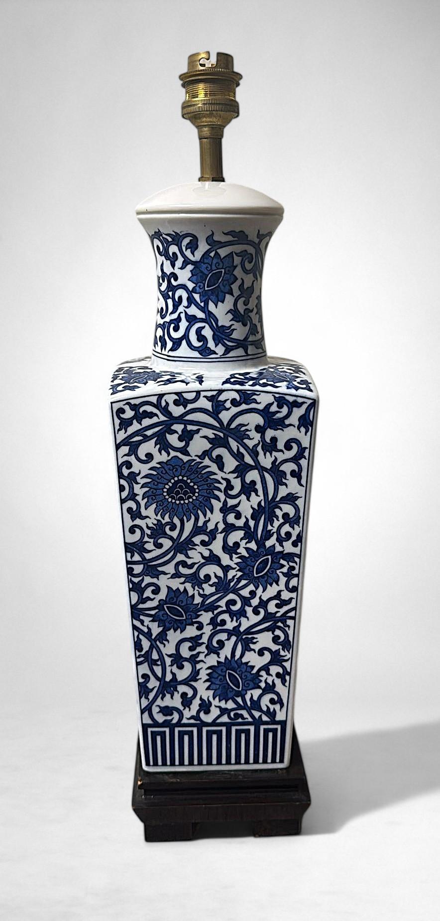 Cette lampe de table chinoise raffinée, fabriquée en porcelaine émaillée bleue et blanche, date très probablement des années 1950-1955. La structure, dont la forme carrée s'affine légèrement vers la base, est entièrement décorée à la main d'élégants