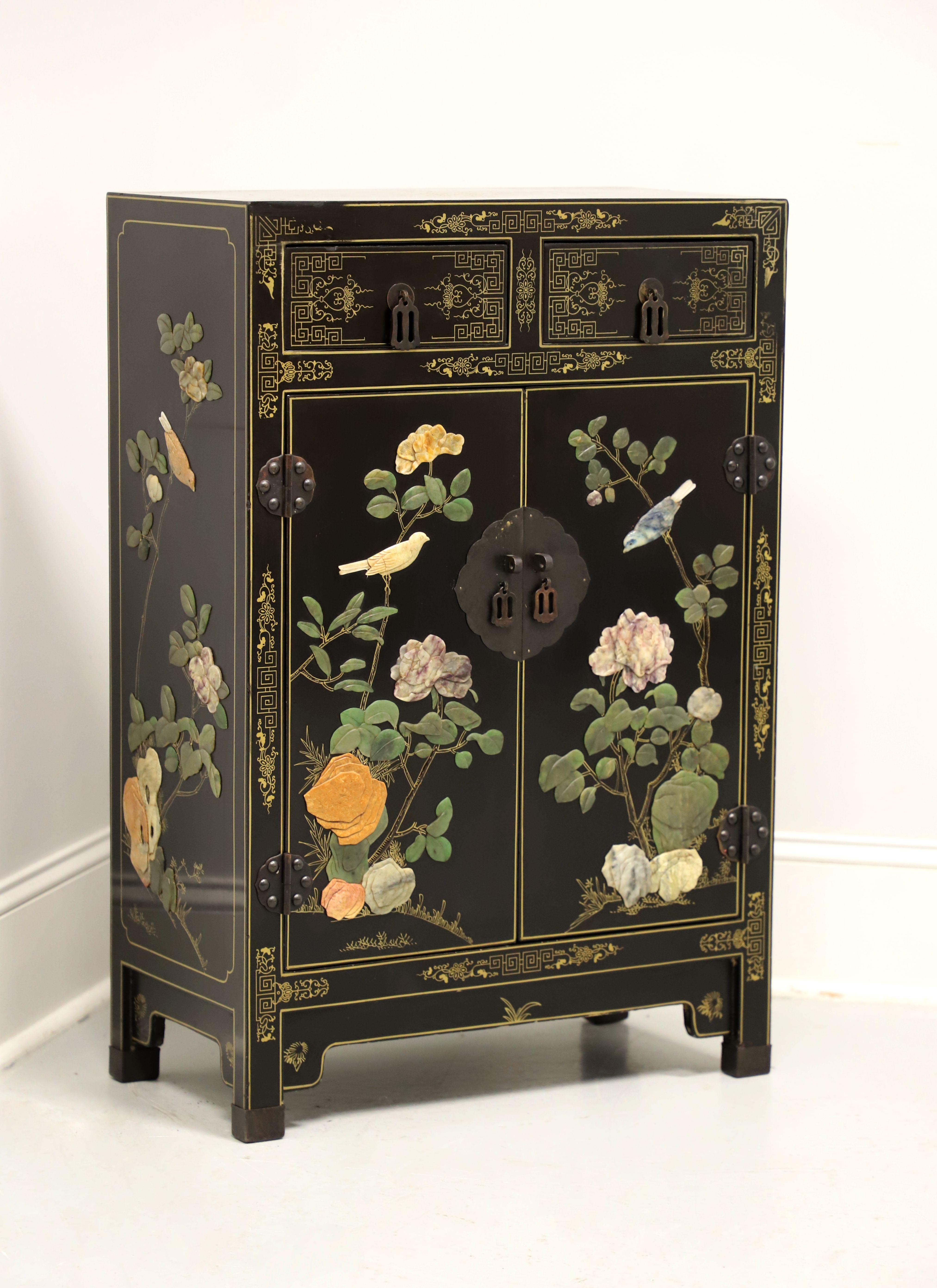 A vintage Asian Chinoiserie style console cabinet by Jinlong. Solid wood with black lacquer, gold painted Chinoiserie pattern to the top, front & drawer fronts, painted gold string inlays, soapstone florals to door fronts, brass hardware, carved