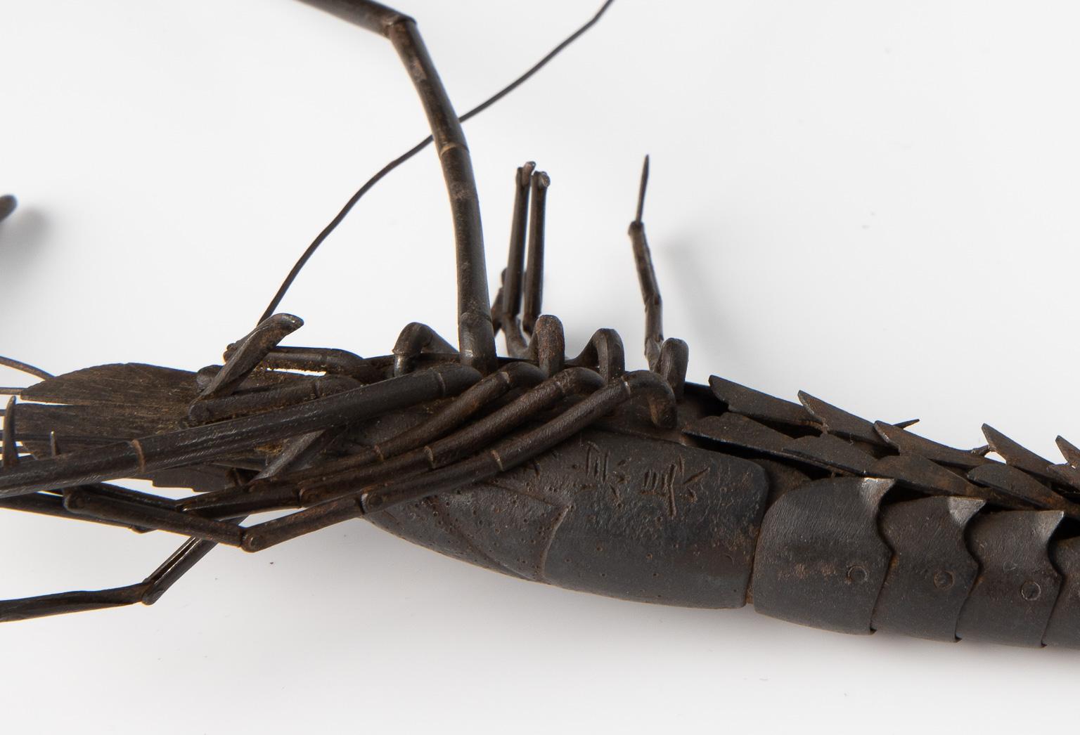 Edo Period (1615-1867), 18th-19th century
Measure: Length: 25 cm including antennae
Signed: Myochin Munenaga

The iron prawn is constructed of numerous hammered plates, jointed inside the body; the claws open, the body bends and the eyes,