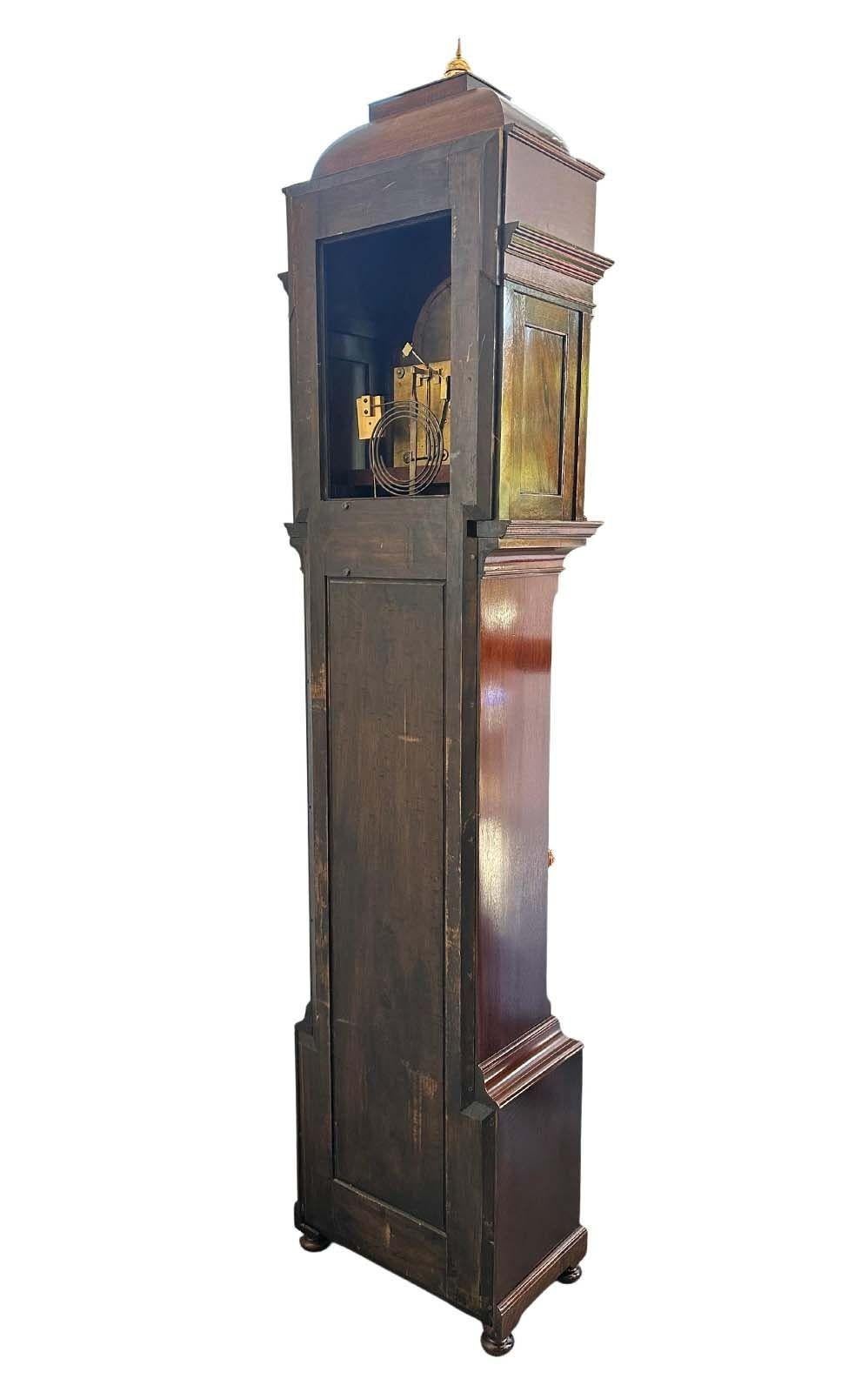 Impressionnante horloge anglaise en acajou de J.J. Elliot, vendu par Tiffany & Co., présente une délicate marqueterie florale. Le capuchon sculptural, orné d'épis de faîtage en laiton, rehausse le caractère artistique de ce magnifique miroir