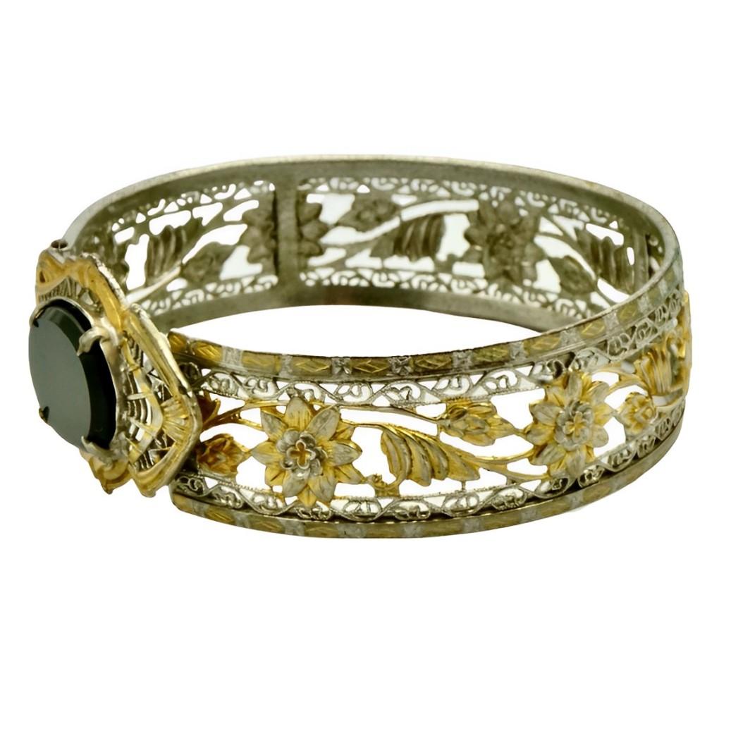 JJ White beautiful Art Deco gold plated and silver plated filigree and flower design bangle, set with a black glass stone. The bangle is oval and measures inside diameter 6 cm / 2.3 inches by 5.5 cm / 2.1 inches. The width is 1.7 cm / .67 inch.
