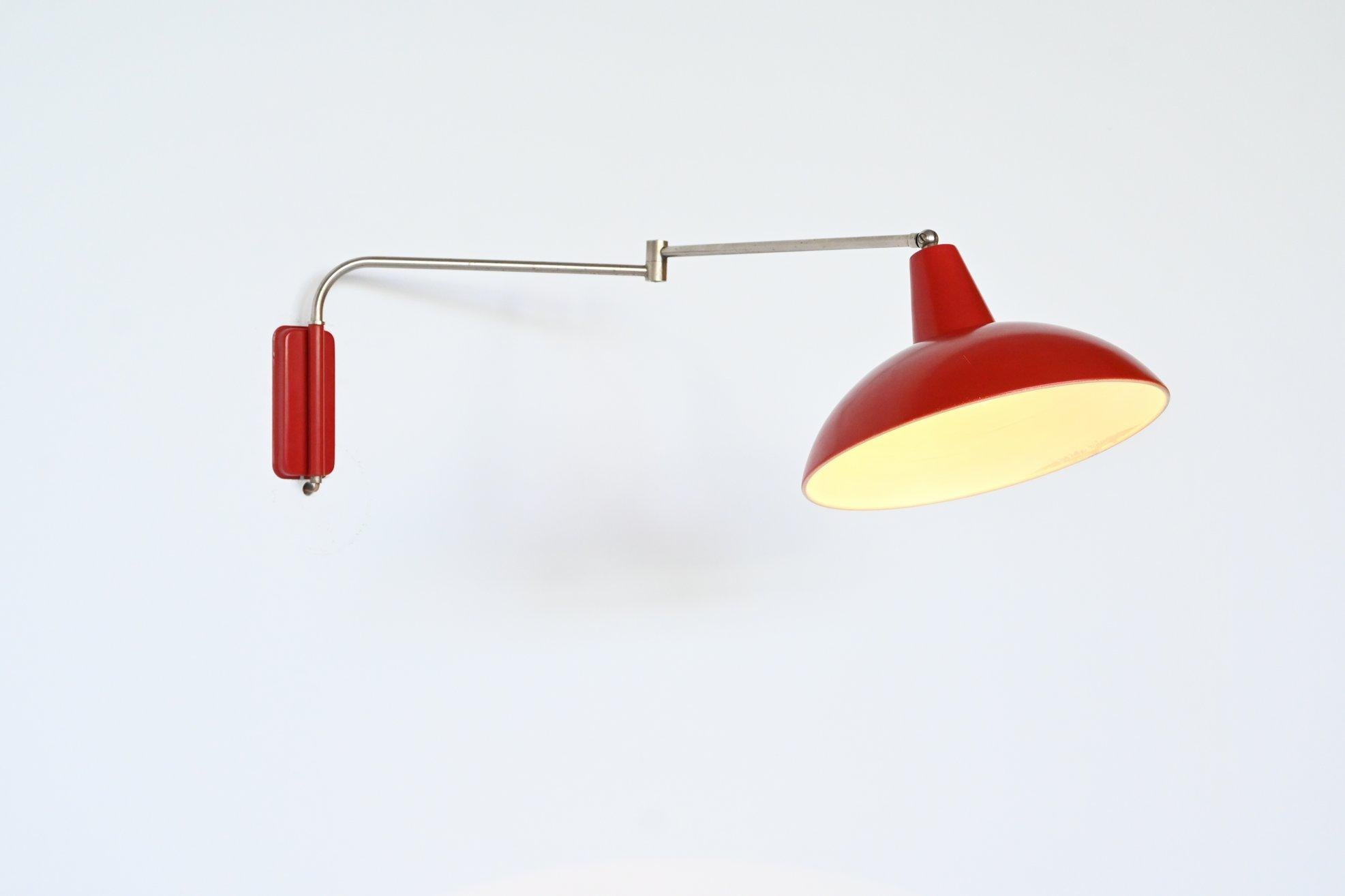 Beautiful and rare wall lamp designed by JJM Hoogervorst for Anvia Almelo, The Netherlands 1950. The lamp has an nickel plated chrome wall arm and original red lacquered shade and wall plate. It is adjustable in many different positions and gives