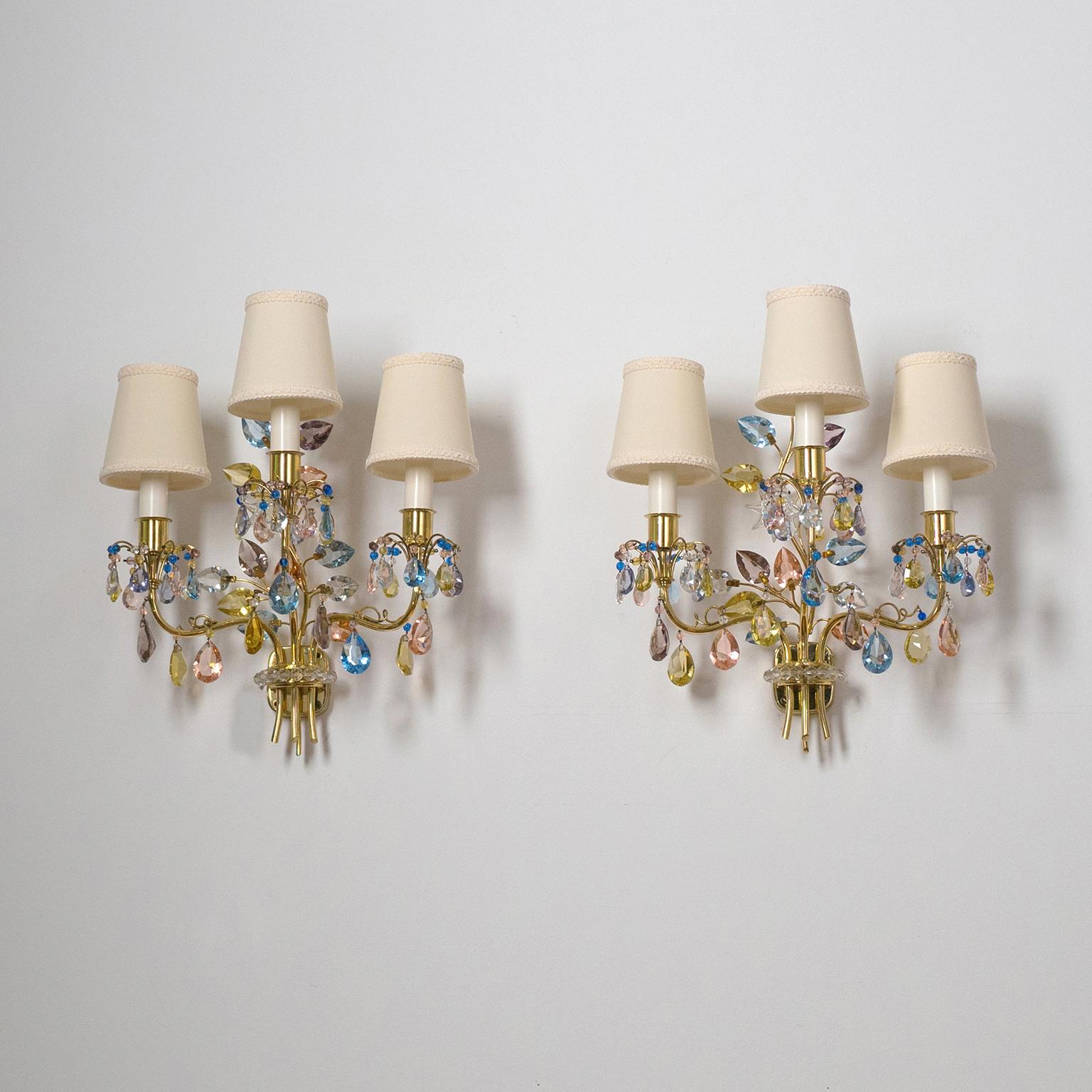 Rare pair of three-arm brass wall lights with colored crystals designed by Oswald Haerdtl for J&L Lobmeyr, 1950s. Intricate brass structure with crystals of varying shapes and colors. Three arms, each with an E14 socket and new custom shades. Priced