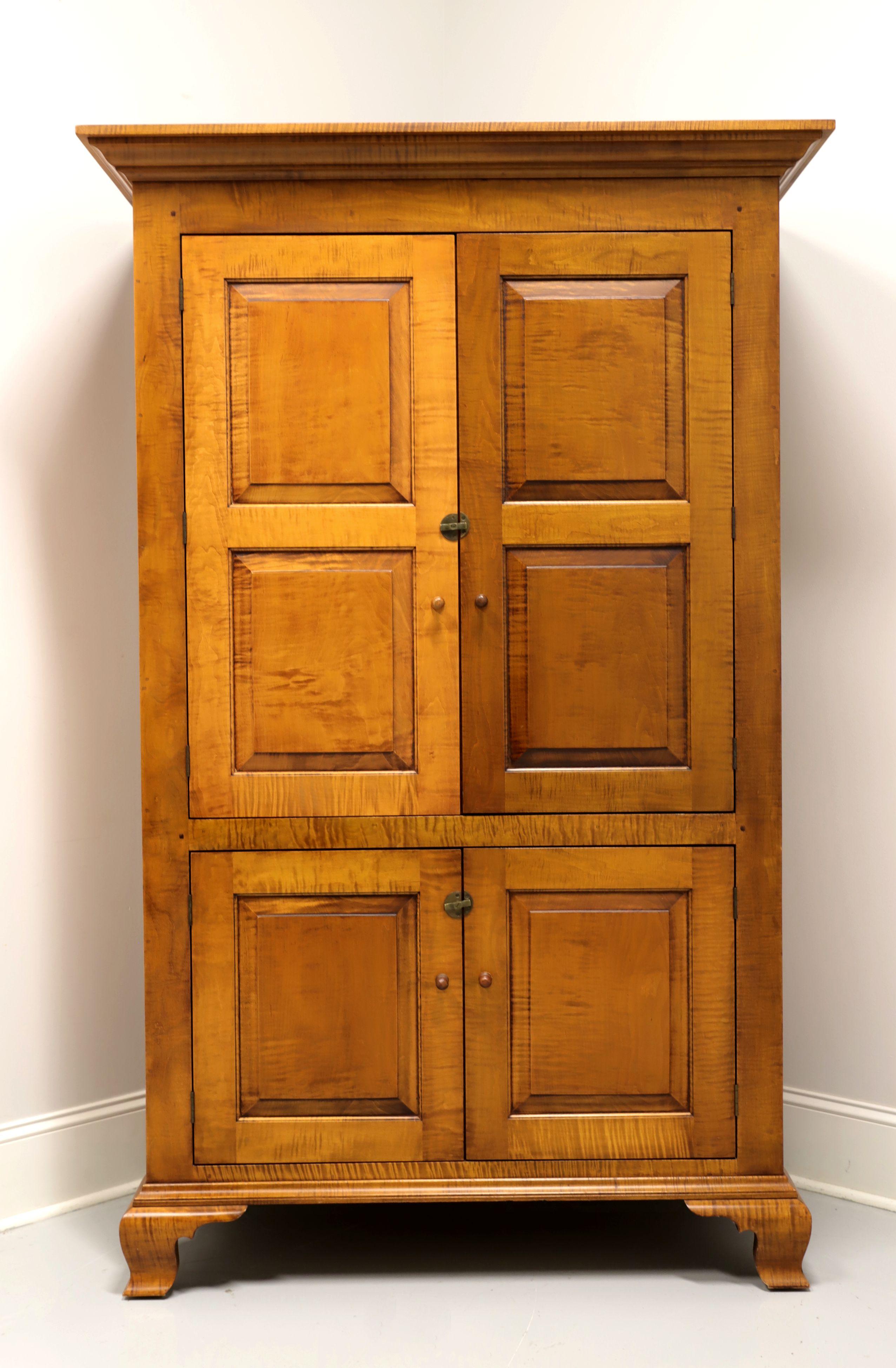 A Chippendale style linen press by JL Treharn. Solid tiger maple with brass hardware, crown molding and ogee bracket feet. Upper cabinet features an ample storage area with two adjustable wood shelves behind dual solid wood doors. Lower cabinet has