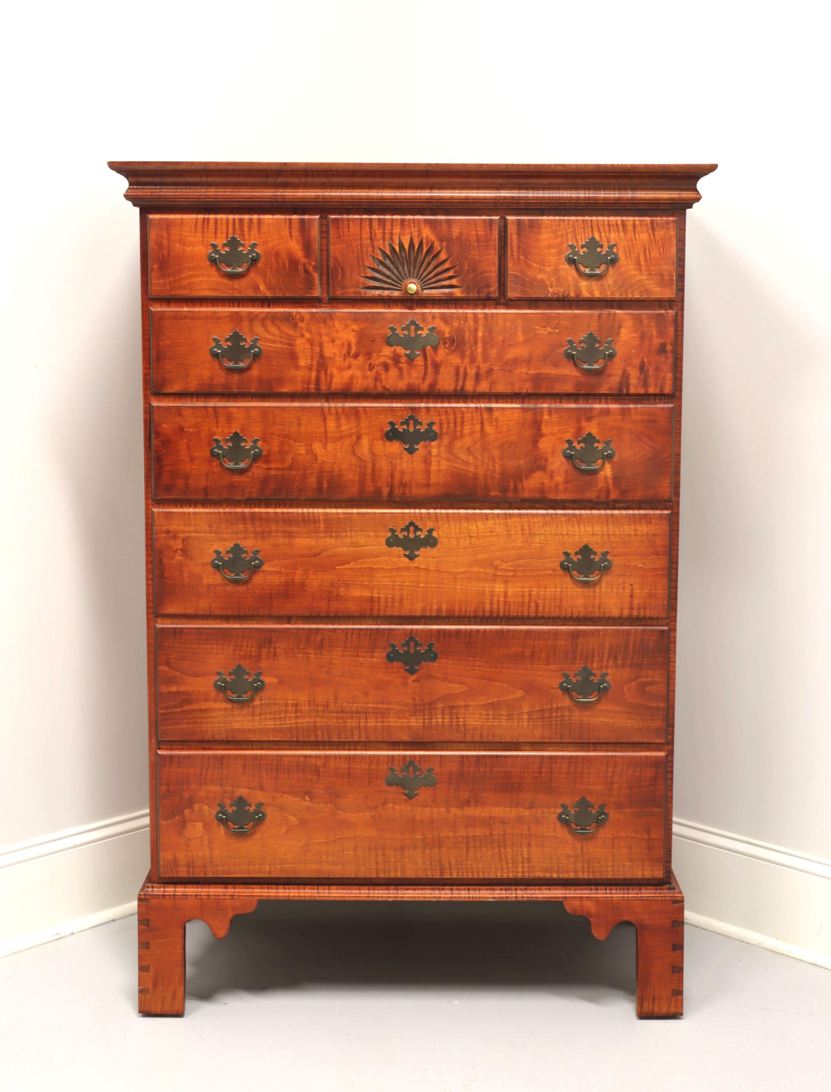 A Chippendale style chest of drawers by JL Treharn. Solid tiger maple with brass hardware, crown molding at top and bracket feet. Features eight various size drawers of dovetail construction. Upper center drawer has decorative carved fan design and