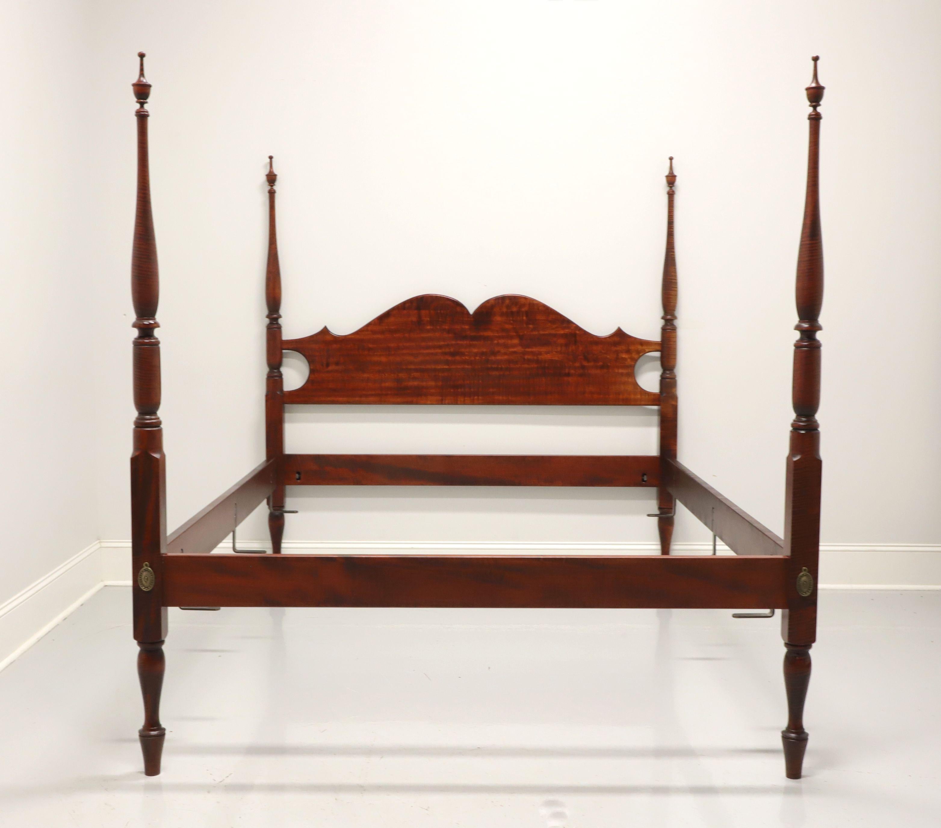 A Sheraton style queen size poster bed by JL Treharn. Solid tiger maple, four turned posts with finials, carved headboard, low footboard to match side rails, turned feet, brass covers to headboard and footboard. Metal mattress supports are mounted