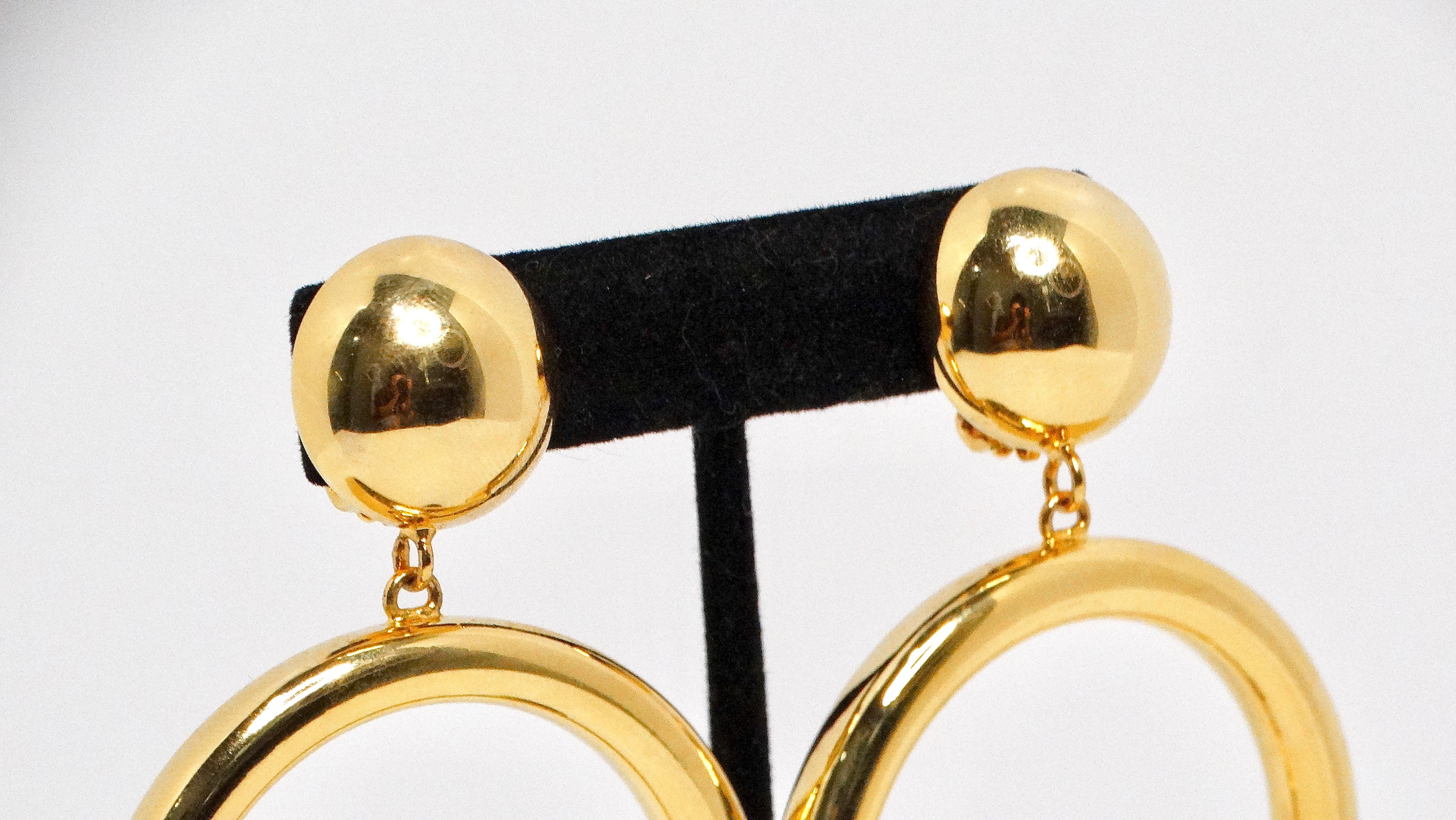 Gli orecchini JLO Hoop Gold Tone Clip-On sono un accessorio divertente e alla moda, perfetto per aggiungere un tocco di glamour al tuo look da giorno. Questi orecchini leggeri sono caratterizzati da un audace design a cerchio che ricorda il classico