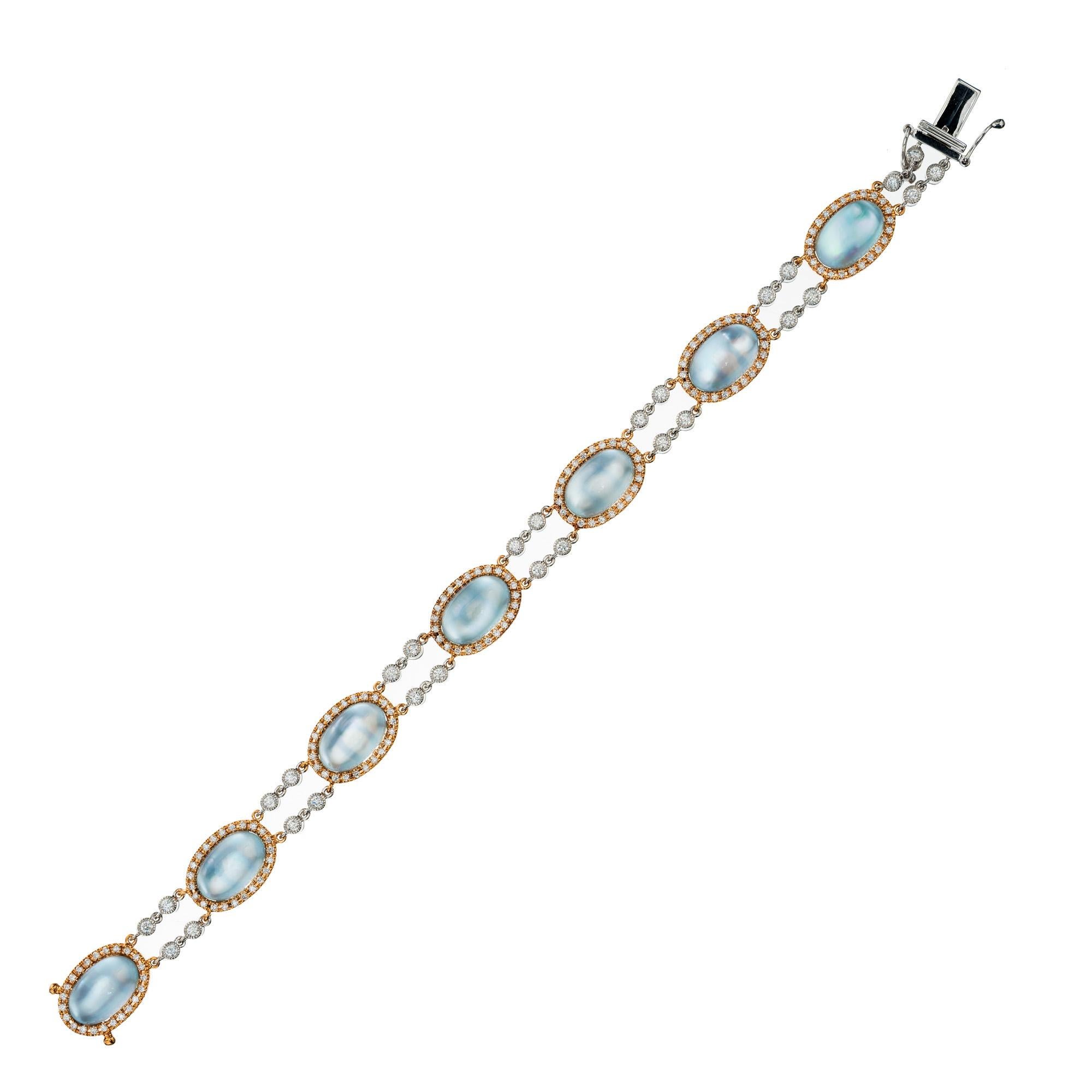 This unique bracelet by Designer JMP, begins with 7 oval cabochon light blue topaz set in 18k rose gold, each with a halo of round cut diamonds. The Topaz are connected by two rows of bezel set diamond links which are 18k white gold. The blue Topaz